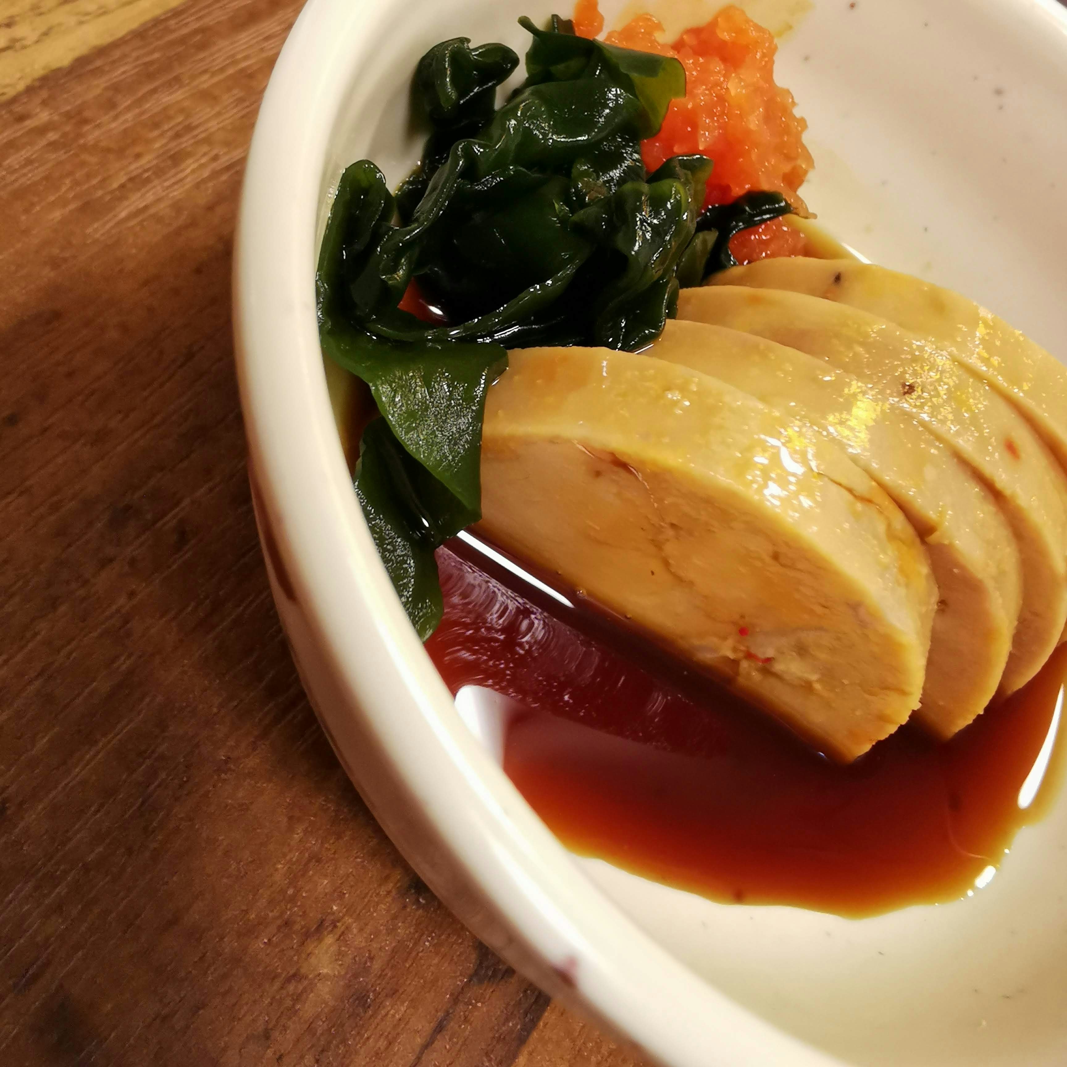 木のまな板の上のスープに浸かった豆腐とわかめ