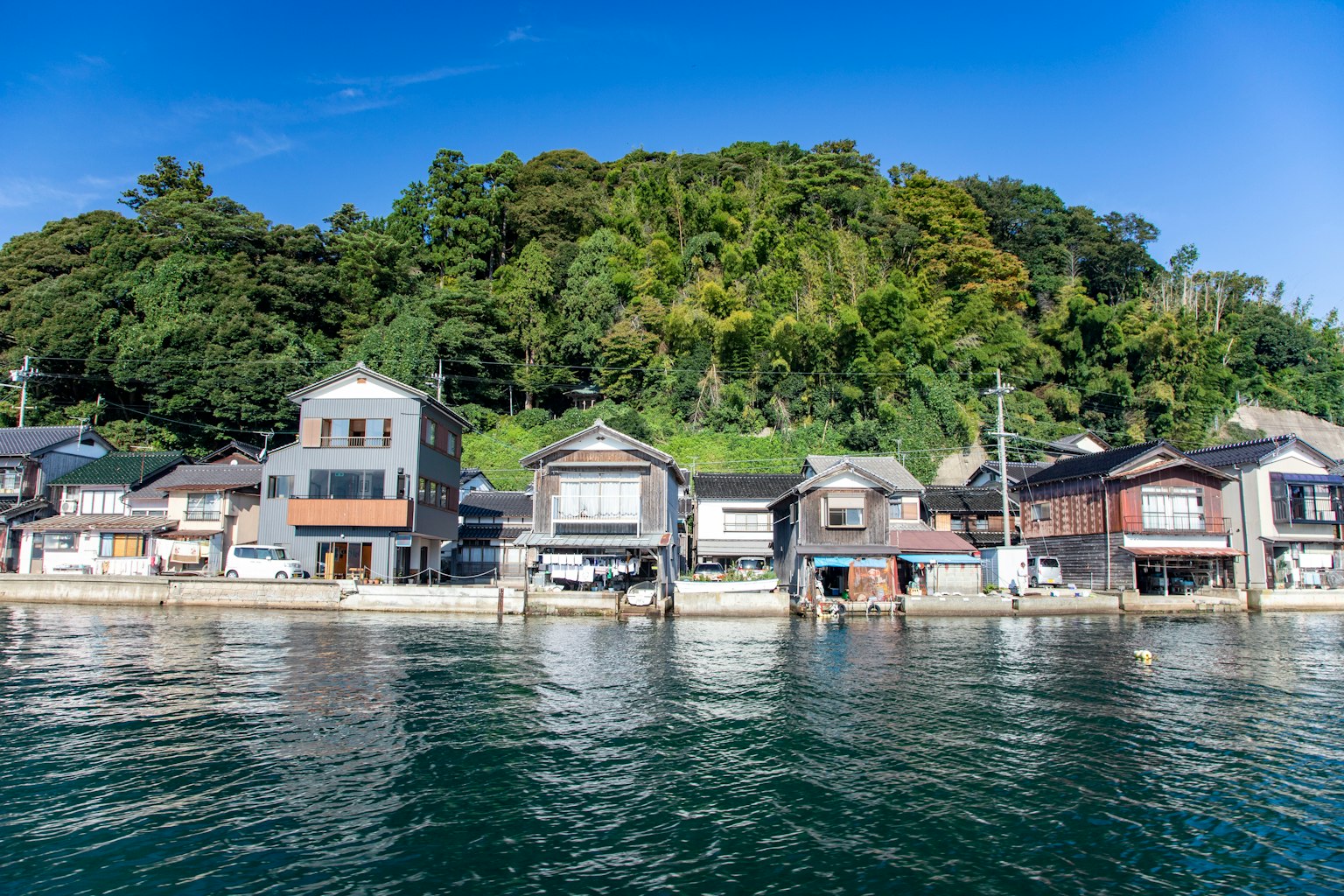 Maisons d'un village de pêcheurs traditionnel au bord de l'eau avec une colline verdoyante