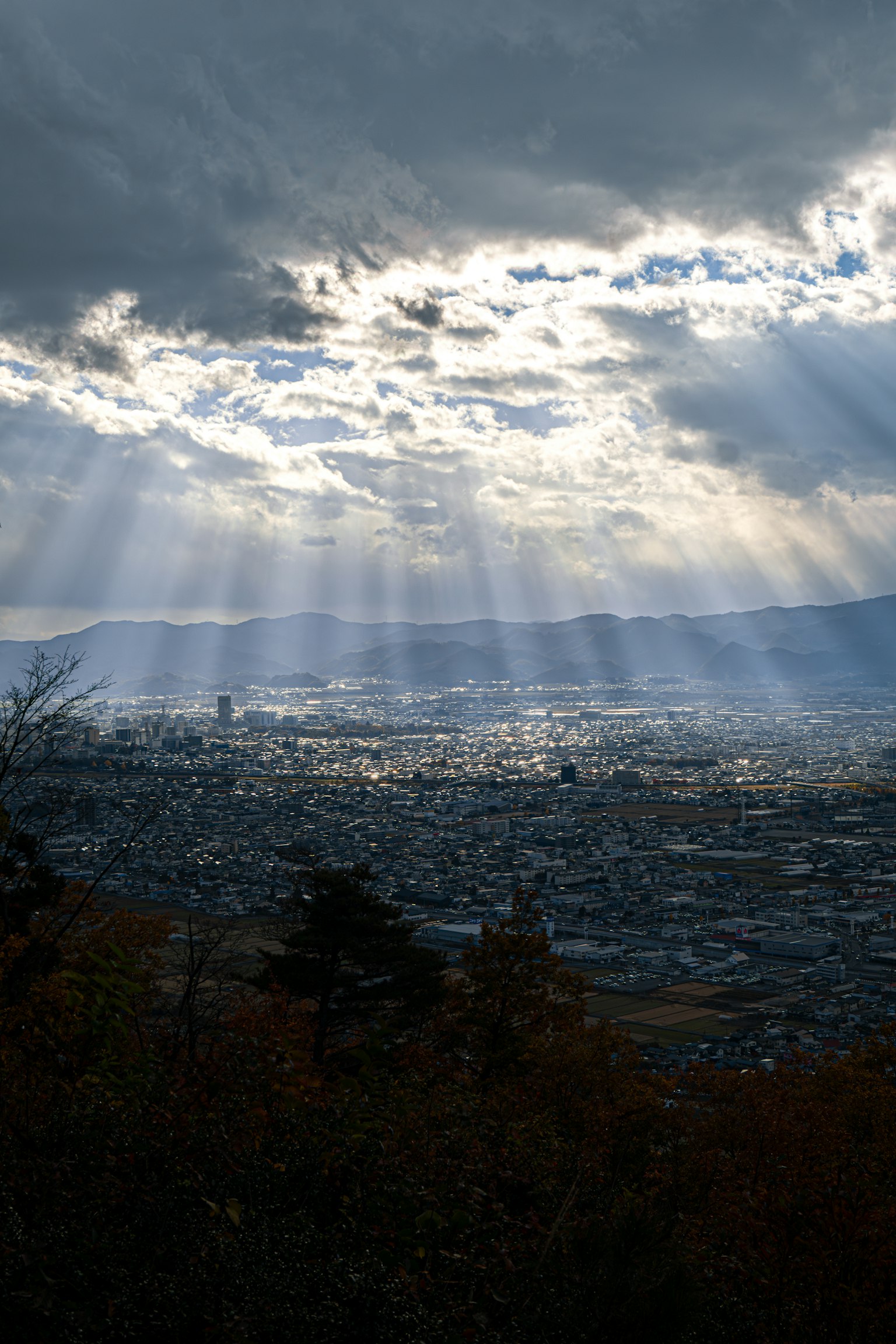 Lumière du soleil filtrant à travers les nuages sur un paysage urbain