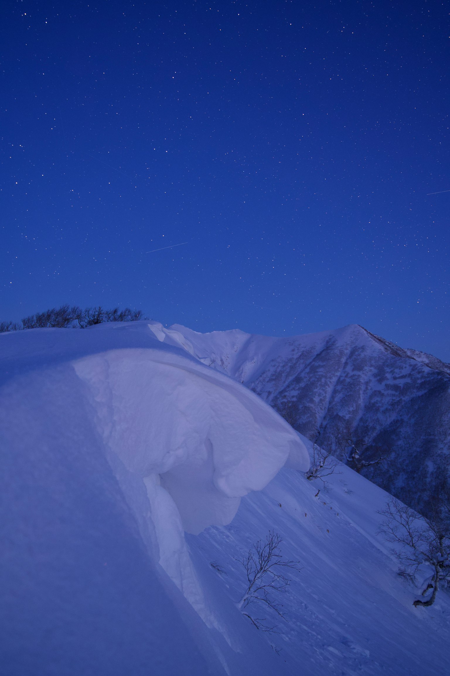 Cresta montuosa coperta di neve sotto un cielo stellato