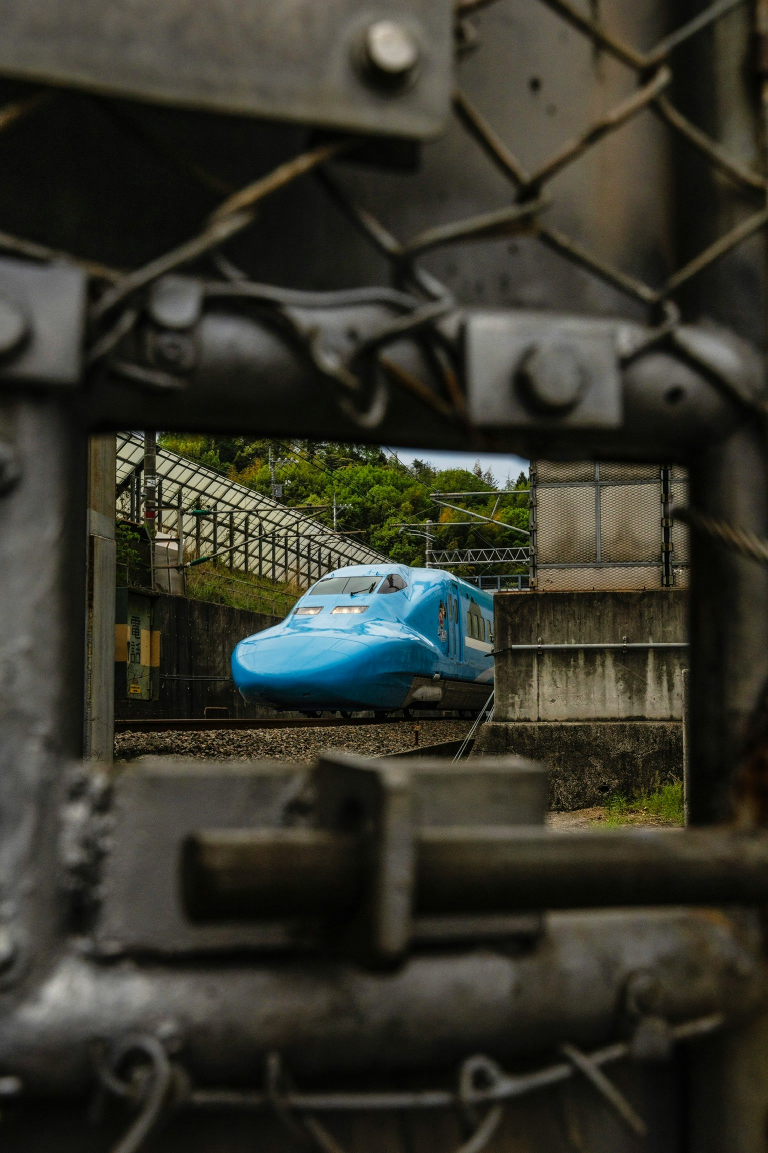 Tàu Shinkansen màu xanh nhìn thấy qua cánh cửa khóa