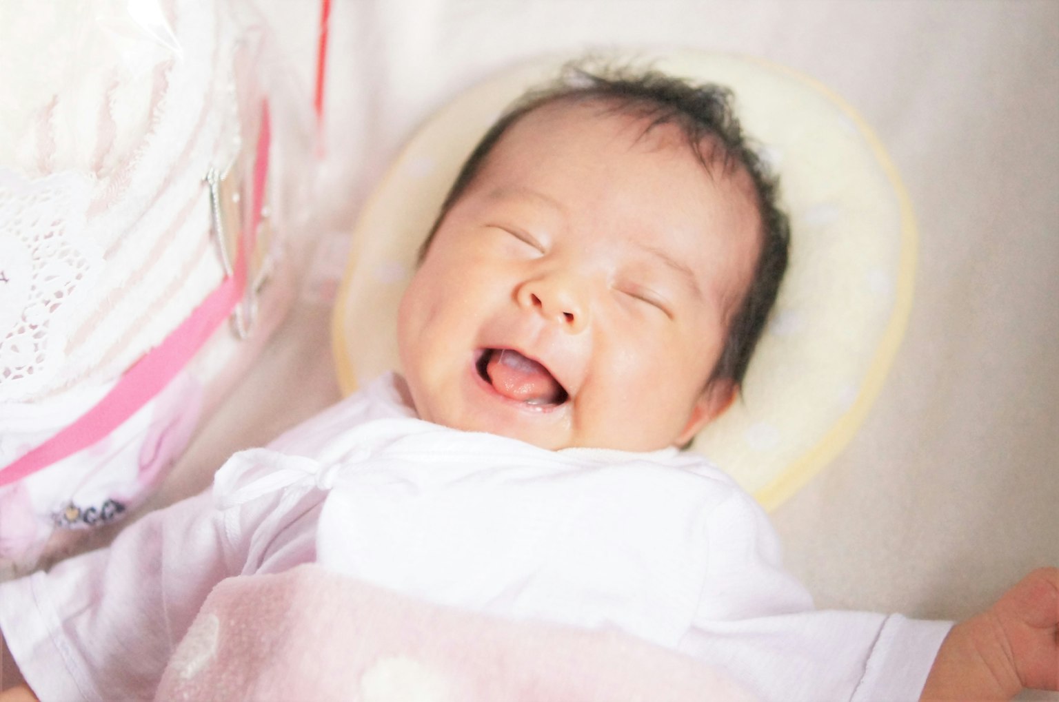 A smiling baby in a white outfit with a happy expression