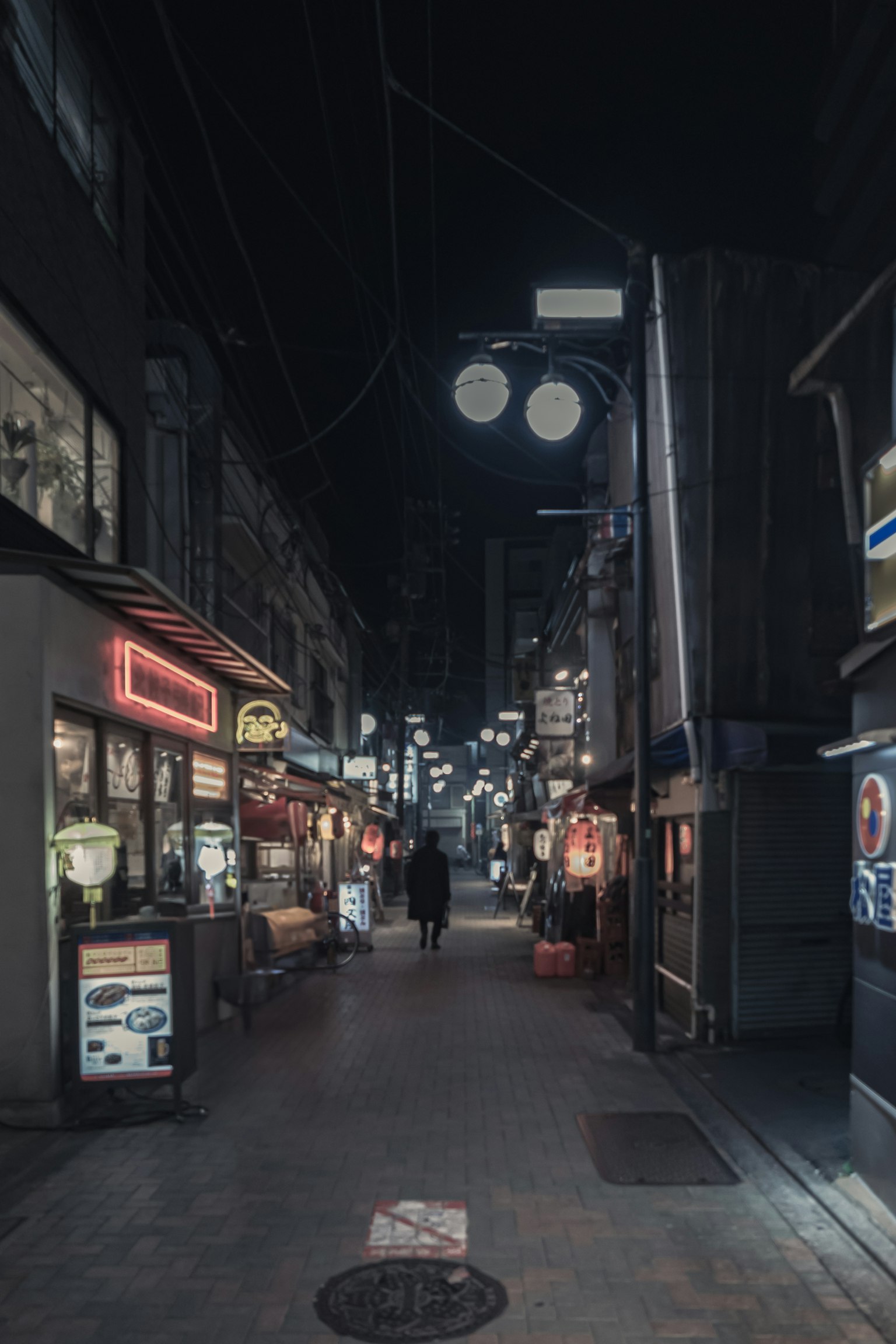 Schmale Straße bei Nacht, gesäumt von beleuchteten Restaurants