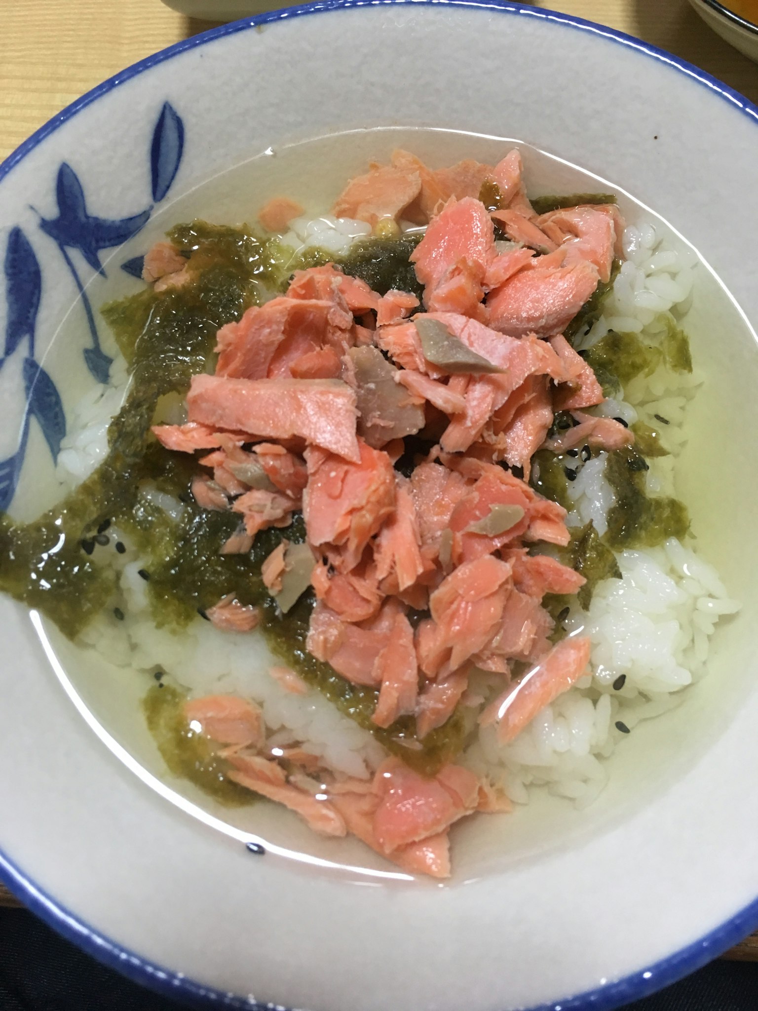 Un tazón de arroz cubierto con salmón y algas en caldo