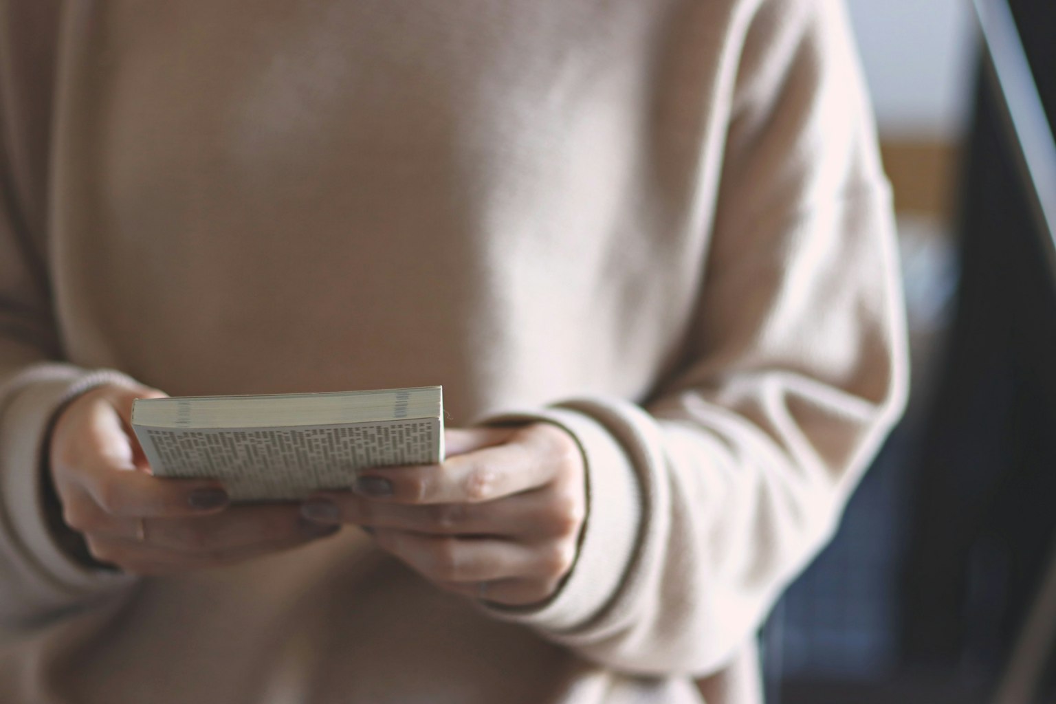 Person in a soft sweater holding a book