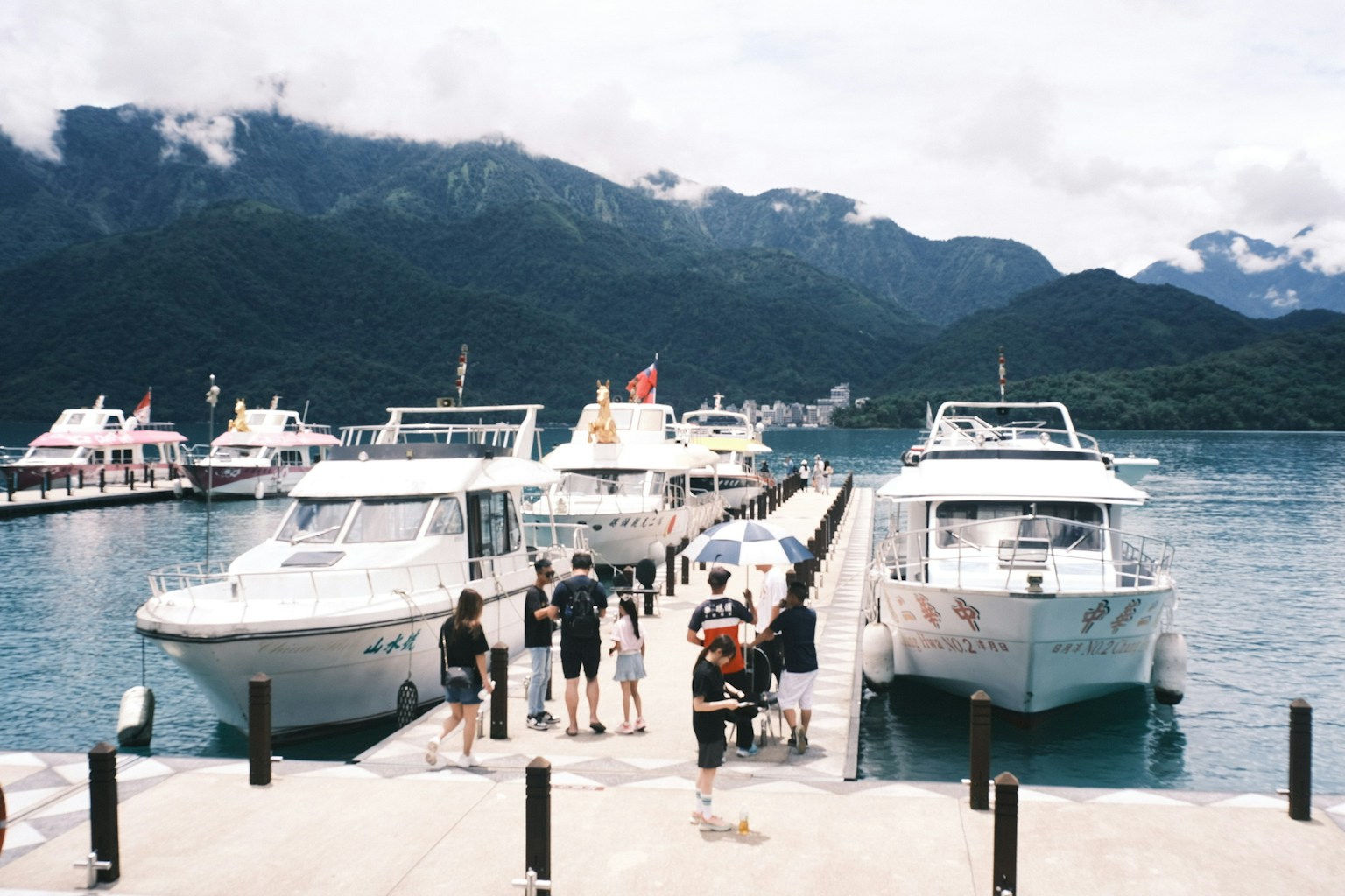 Bateaux amarrés dans un port entouré de montagnes avec des touristes
