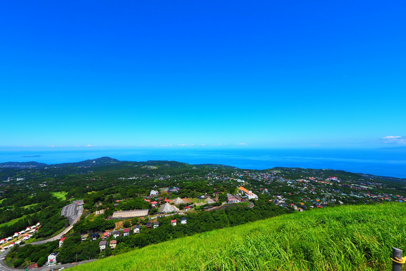 วิวสวยงามของเนินเขาสีเขียวที่มองเห็นมหาสมุทรสีน้ำเงินและท้องฟ้าที่ใส