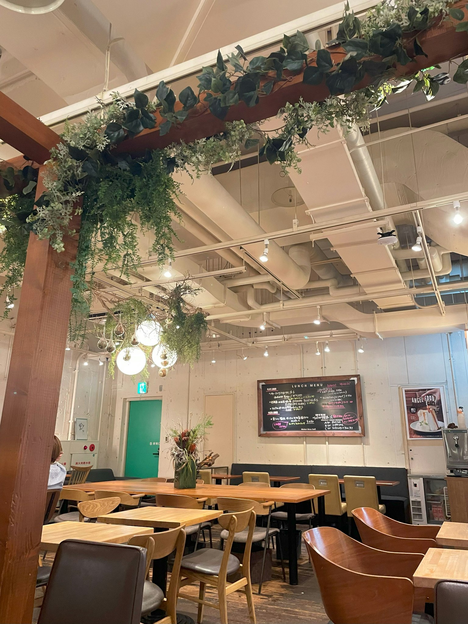Interior de una cafetería con decoración verde y mesas de madera
