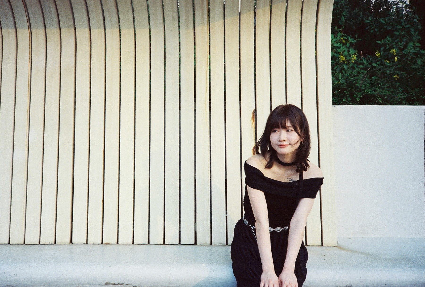 柱のある建物の前で黒いドレスの女性が座っている