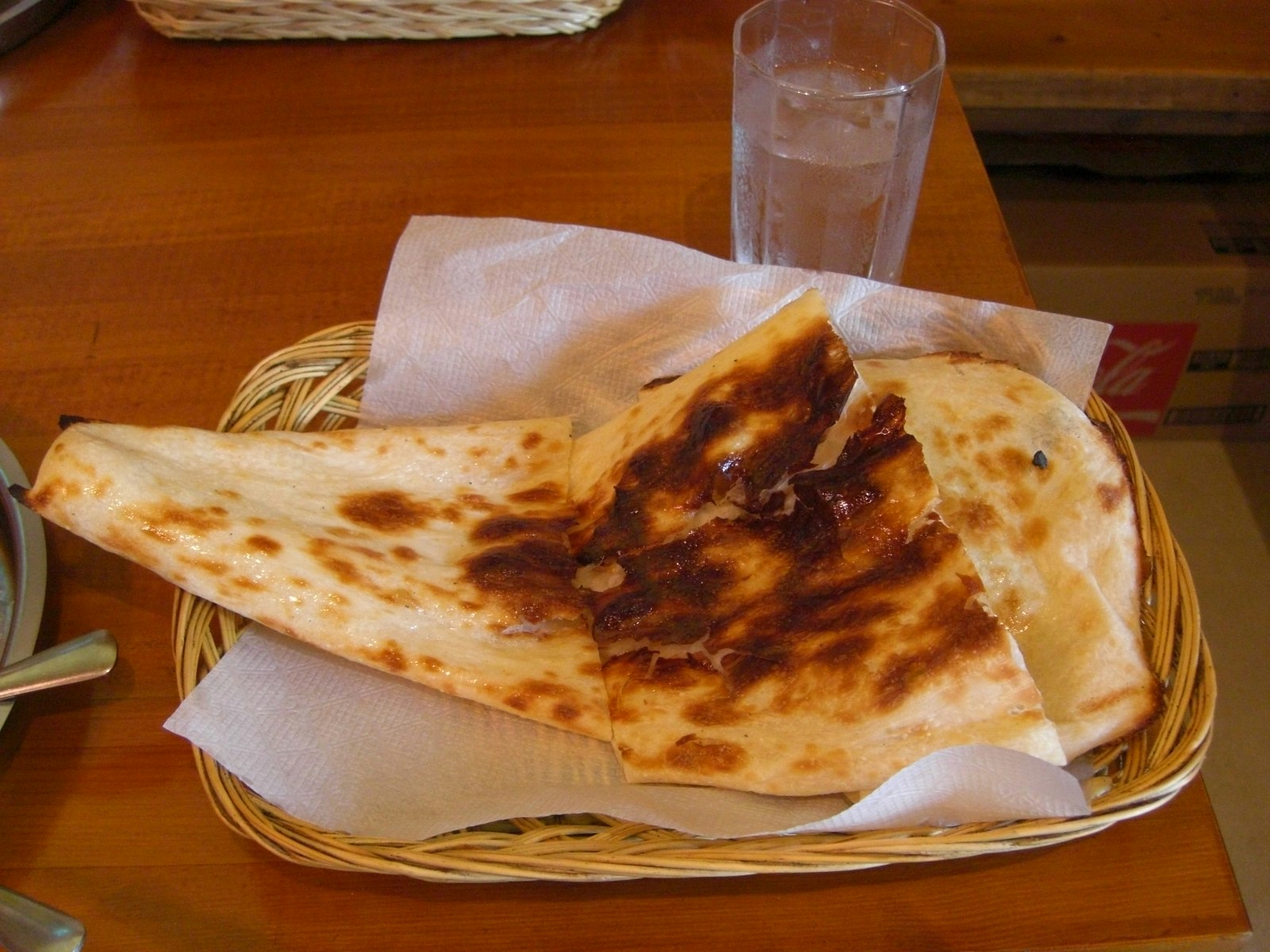 Freshly baked naan in a basket on a wooden table