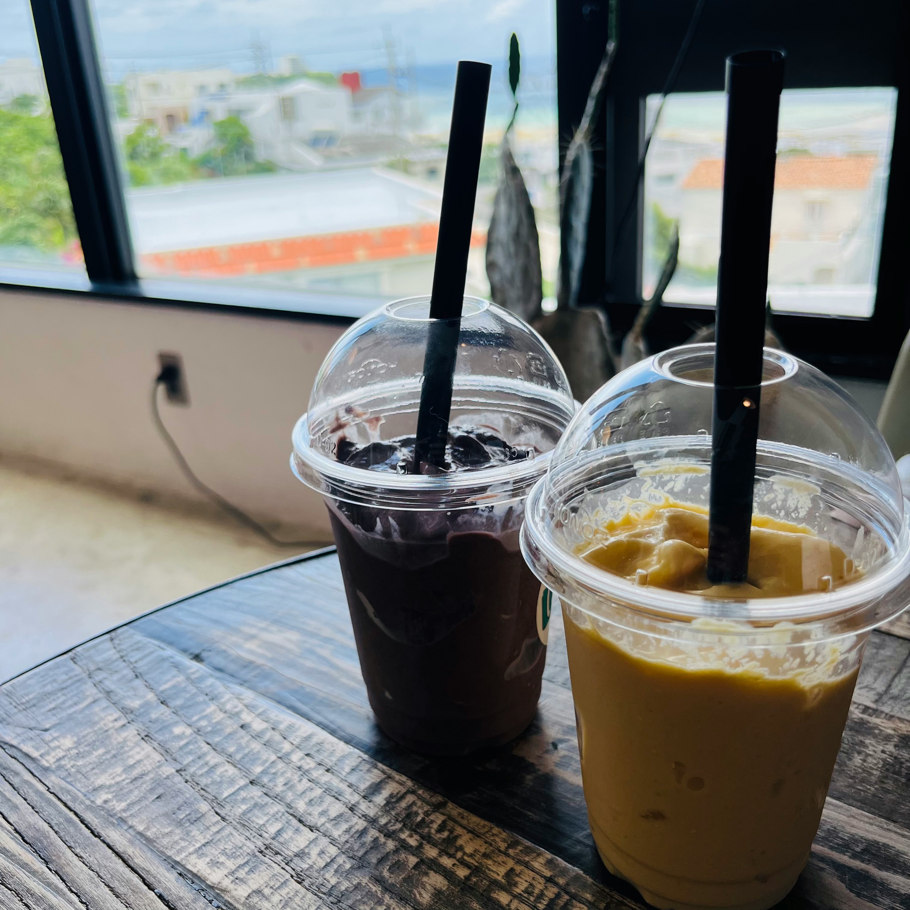 two cups of drinks on a table by the window image