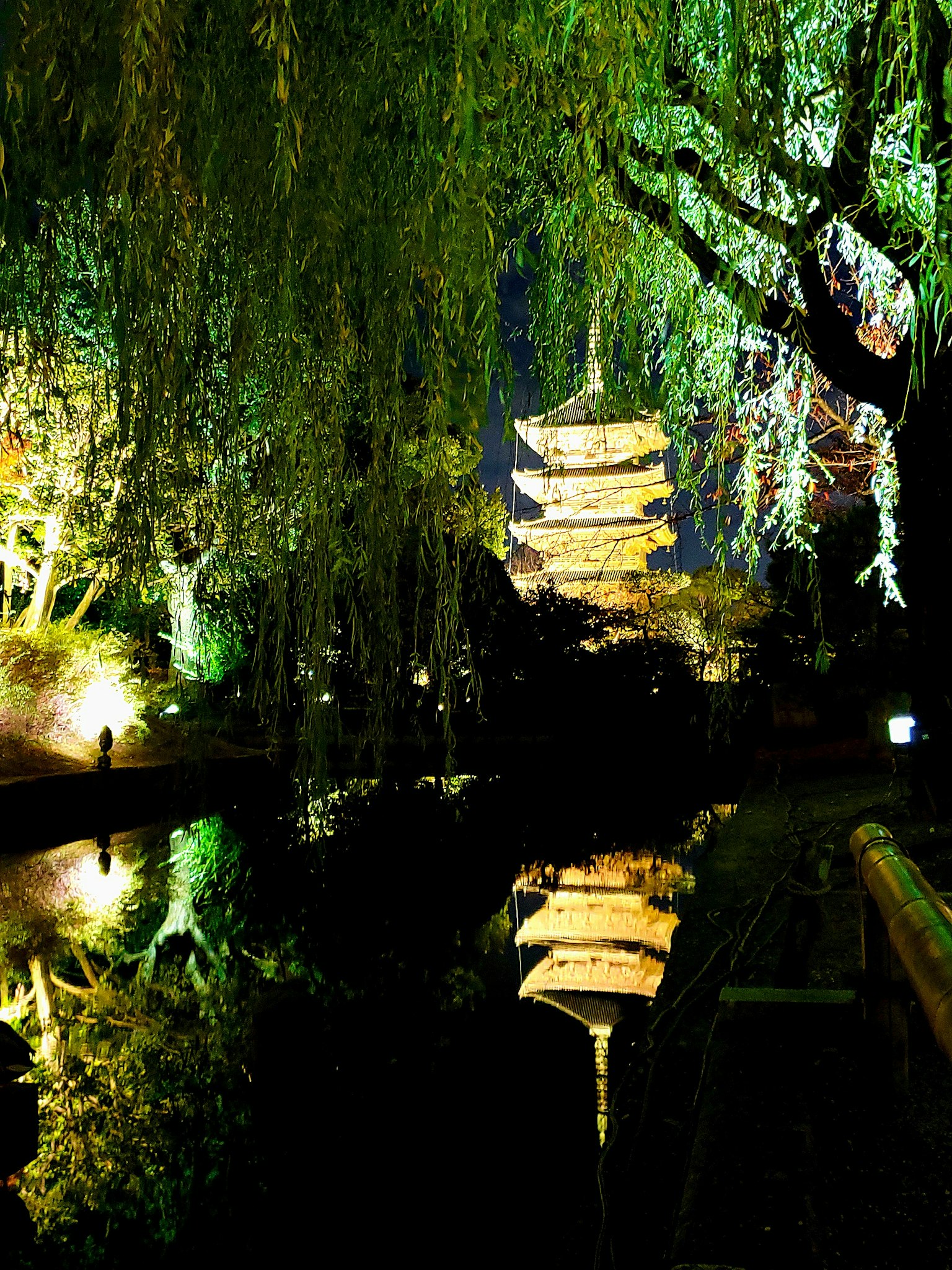 Bella pagoda giapponese riflessa nell'acqua calma circondata da salici di notte