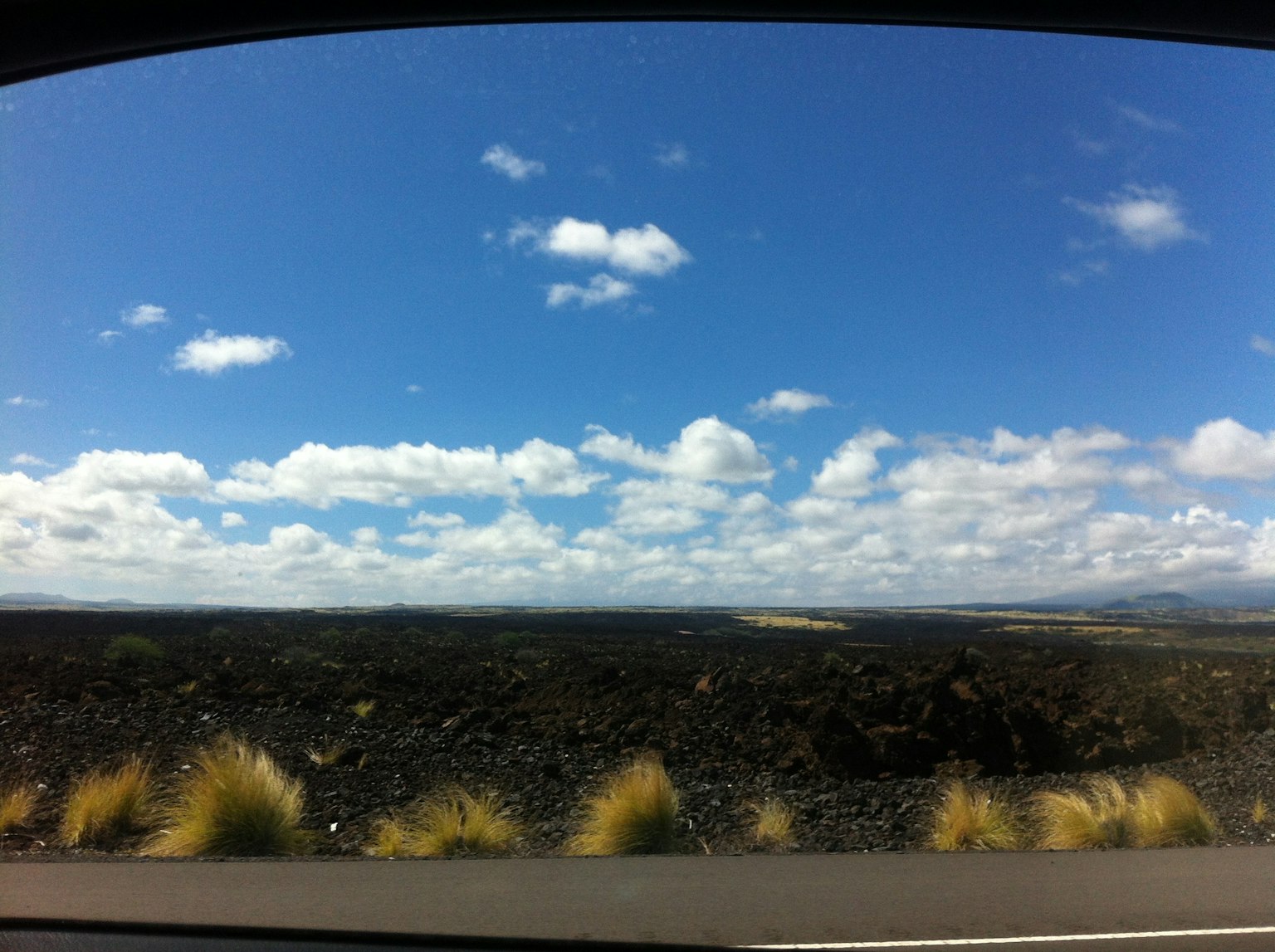 Vue panoramique du ciel bleu avec des nuages blancs sur un paysage de lave noire et d'herbe