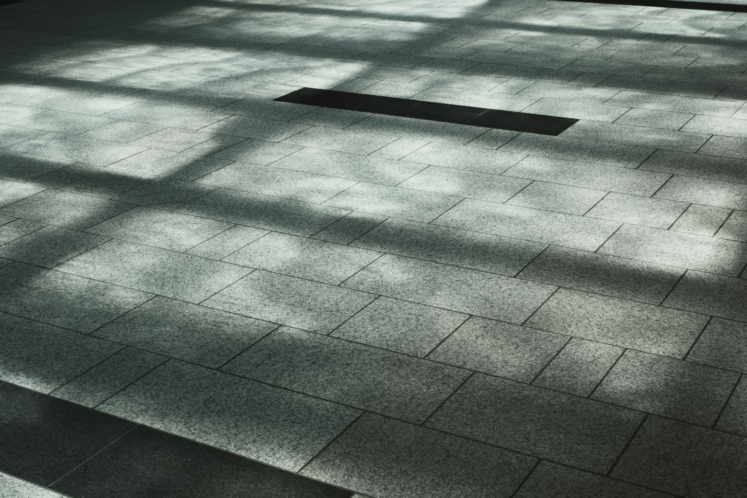 Muster der Bodenfliesen mit Lichtreflexionen und Schatten