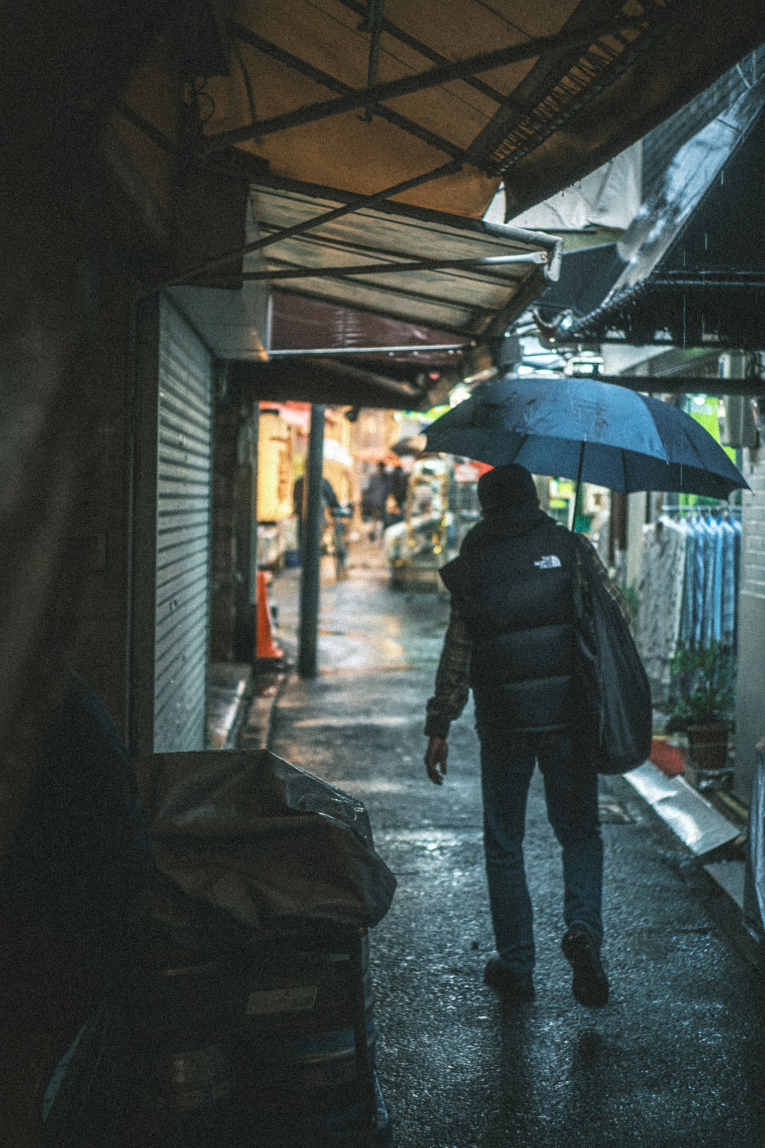 비 오는 날 좁은 거리에서 우산을 쓰고 걷는 사람