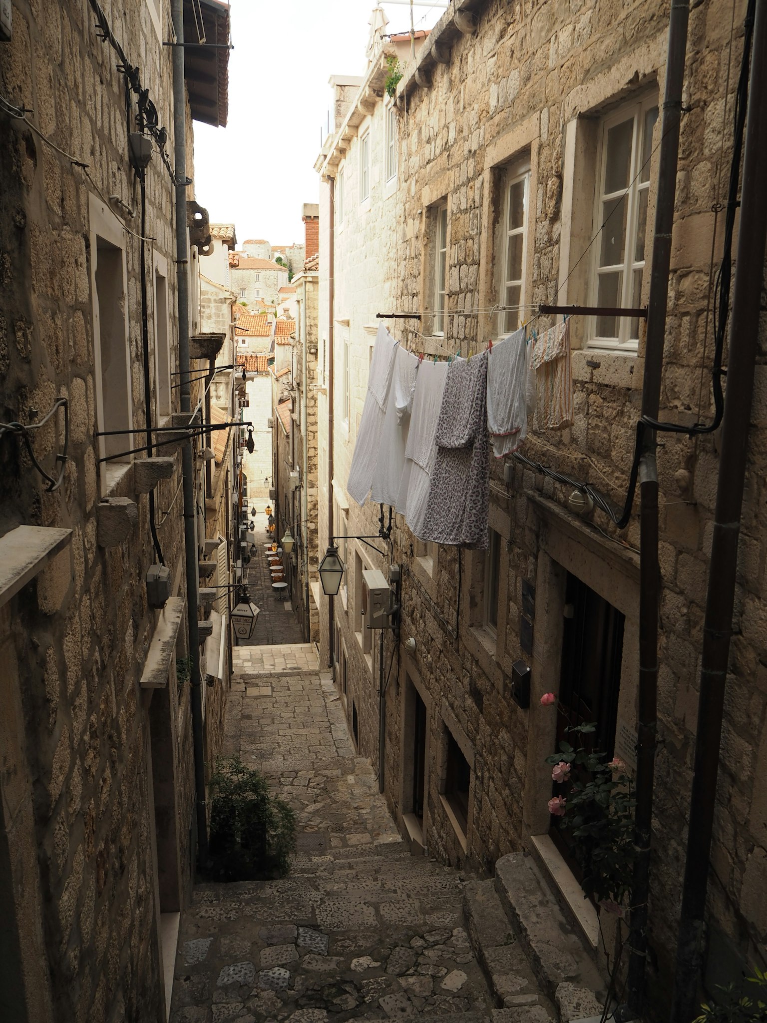 Narrow stone alley with white laundry hanging and old buildings