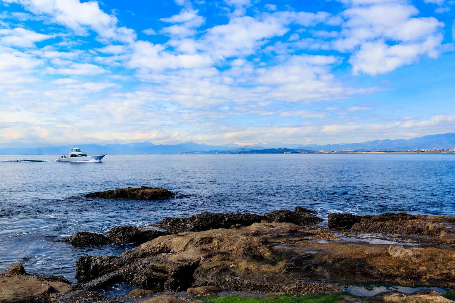 Barco flotando en la costa bajo un cielo azul con nubes