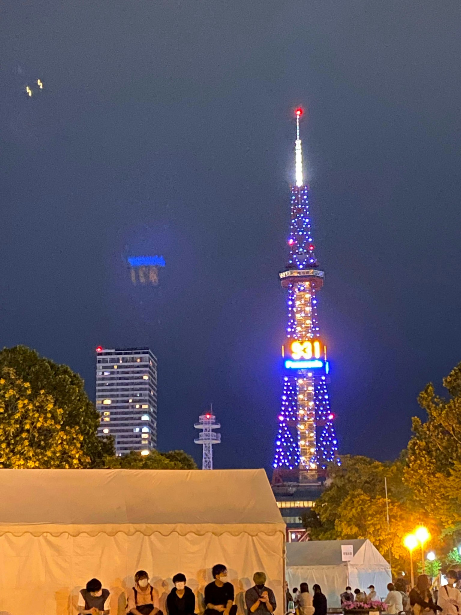 Menara TV Nagoya yang diterangi di malam hari dengan orang-orang di latar depan