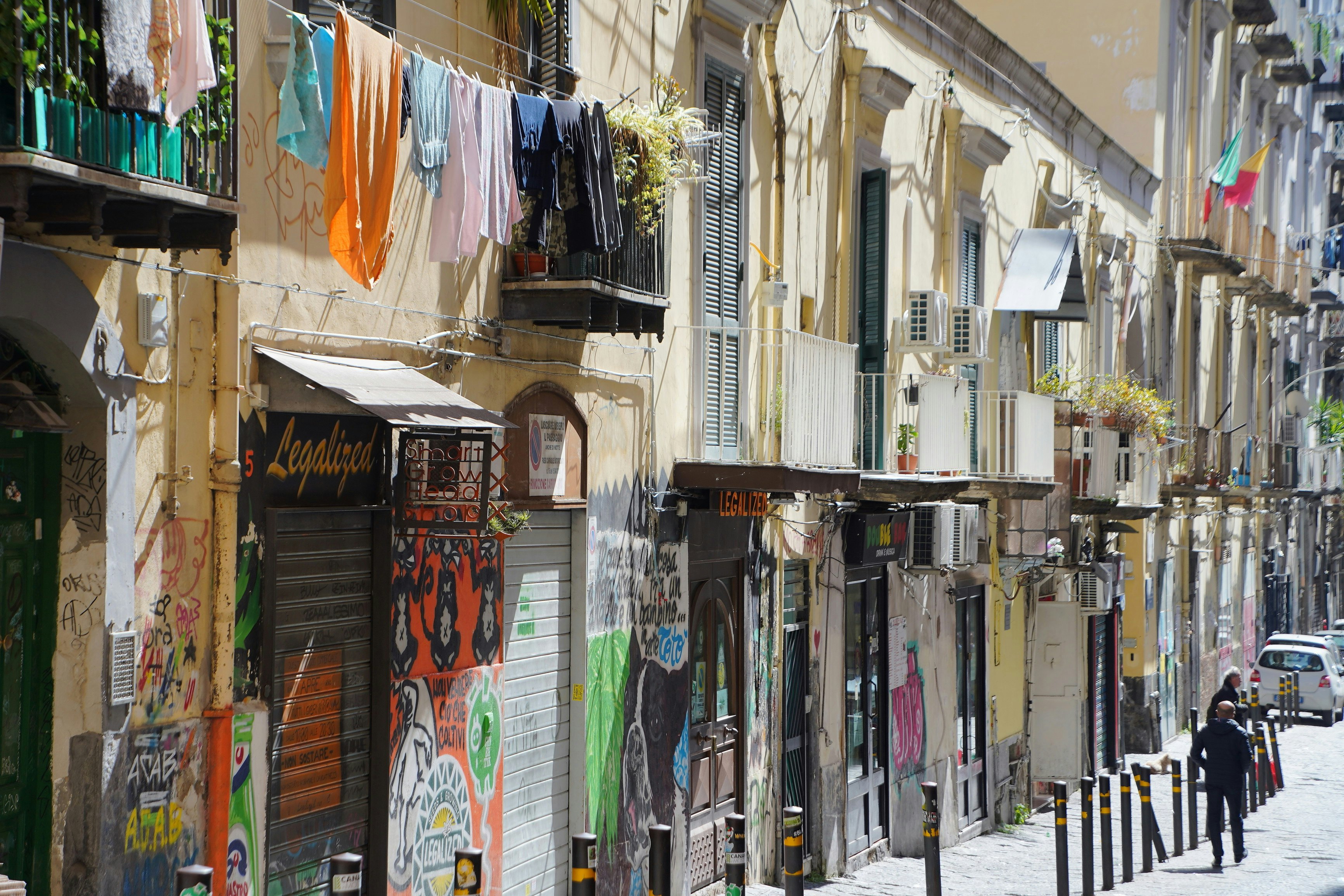 escena callejera de Nápoles con ropa tendida en un callejón y comercios