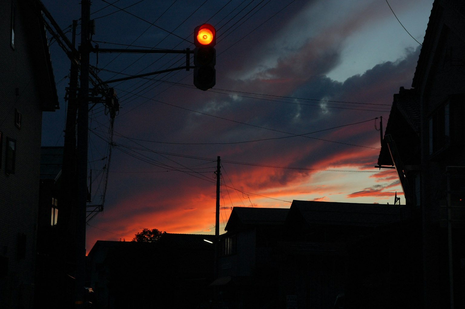 Rote Ampel silhouettiert vor einem Sonnenuntergangshimmel