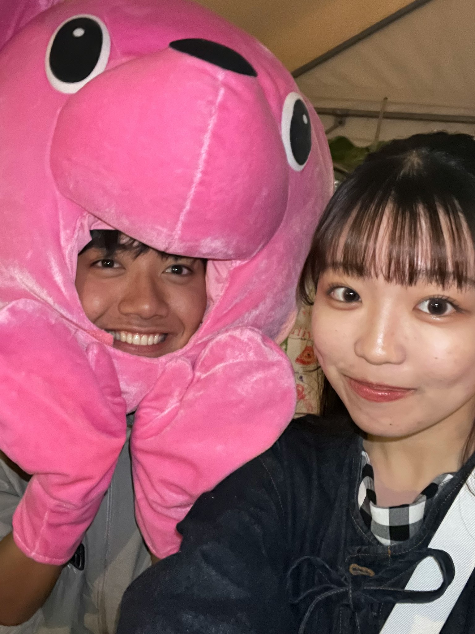 A man wearing a pink plush bear hat smiling next to a woman posing for the camera
