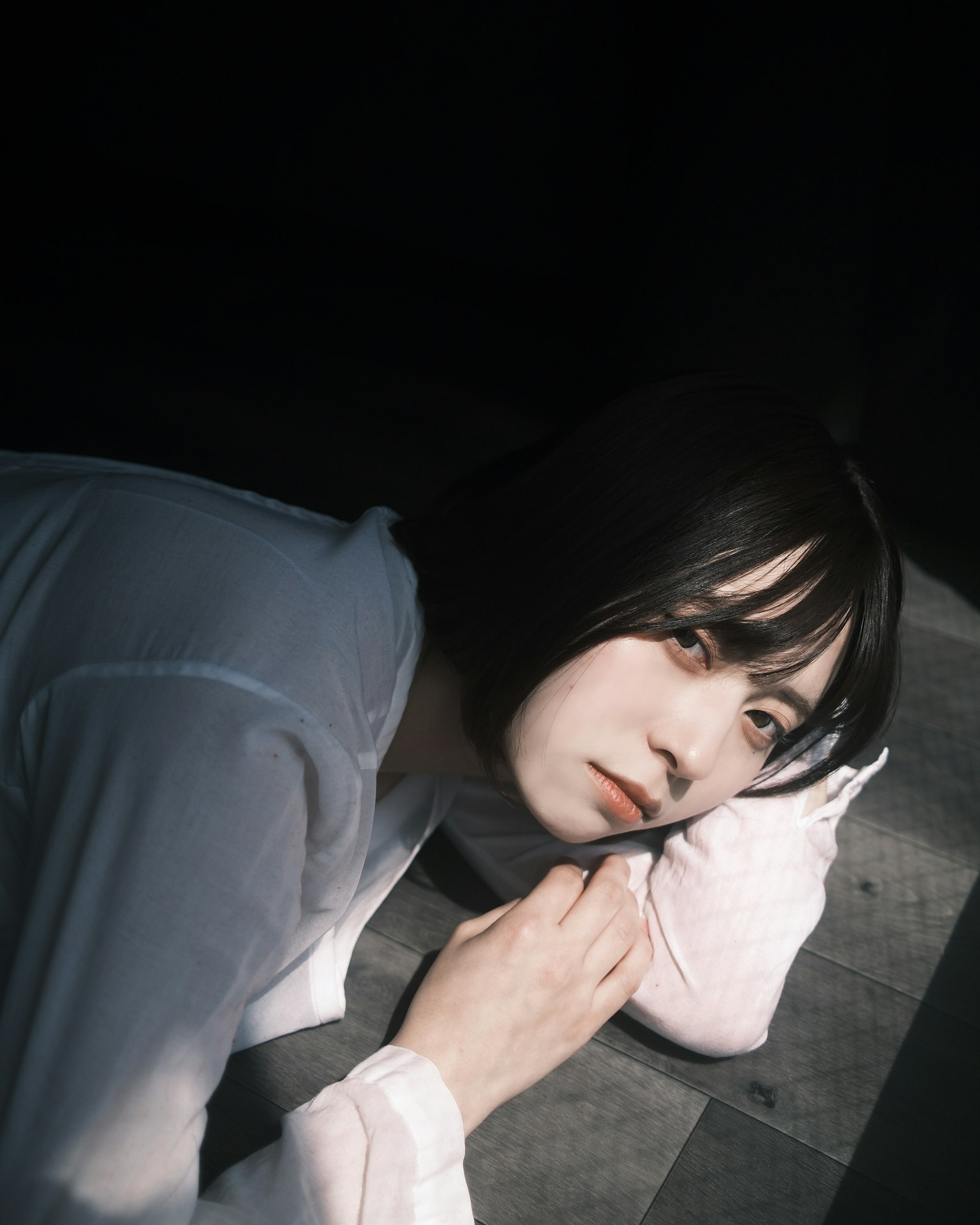 薄暗い部屋で横たわる女性のポートレート 柔らかな光が顔を照らす