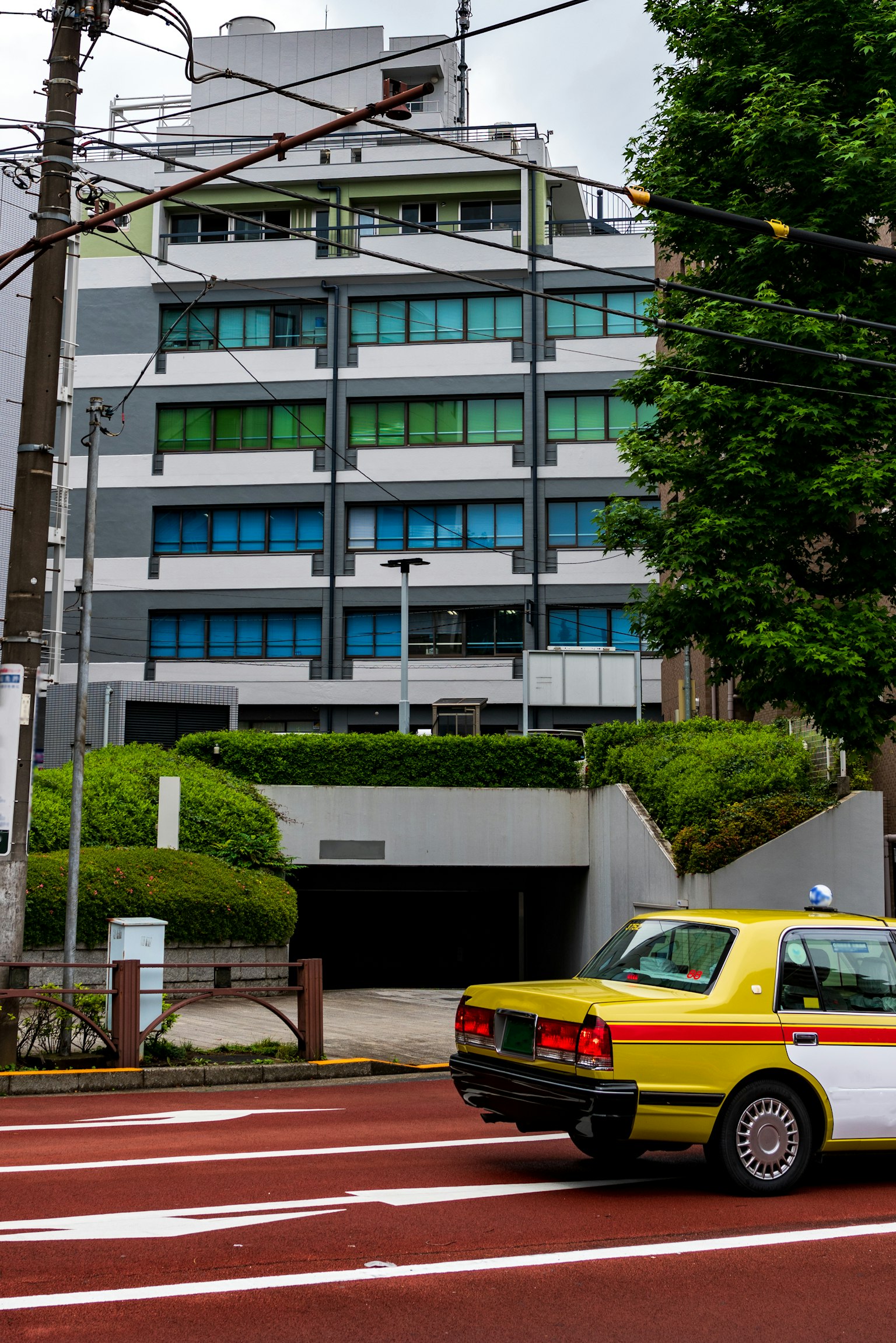 Bâtiment moderne avec fenêtres vertes et bleues et un taxi jaune passant à l'intersection