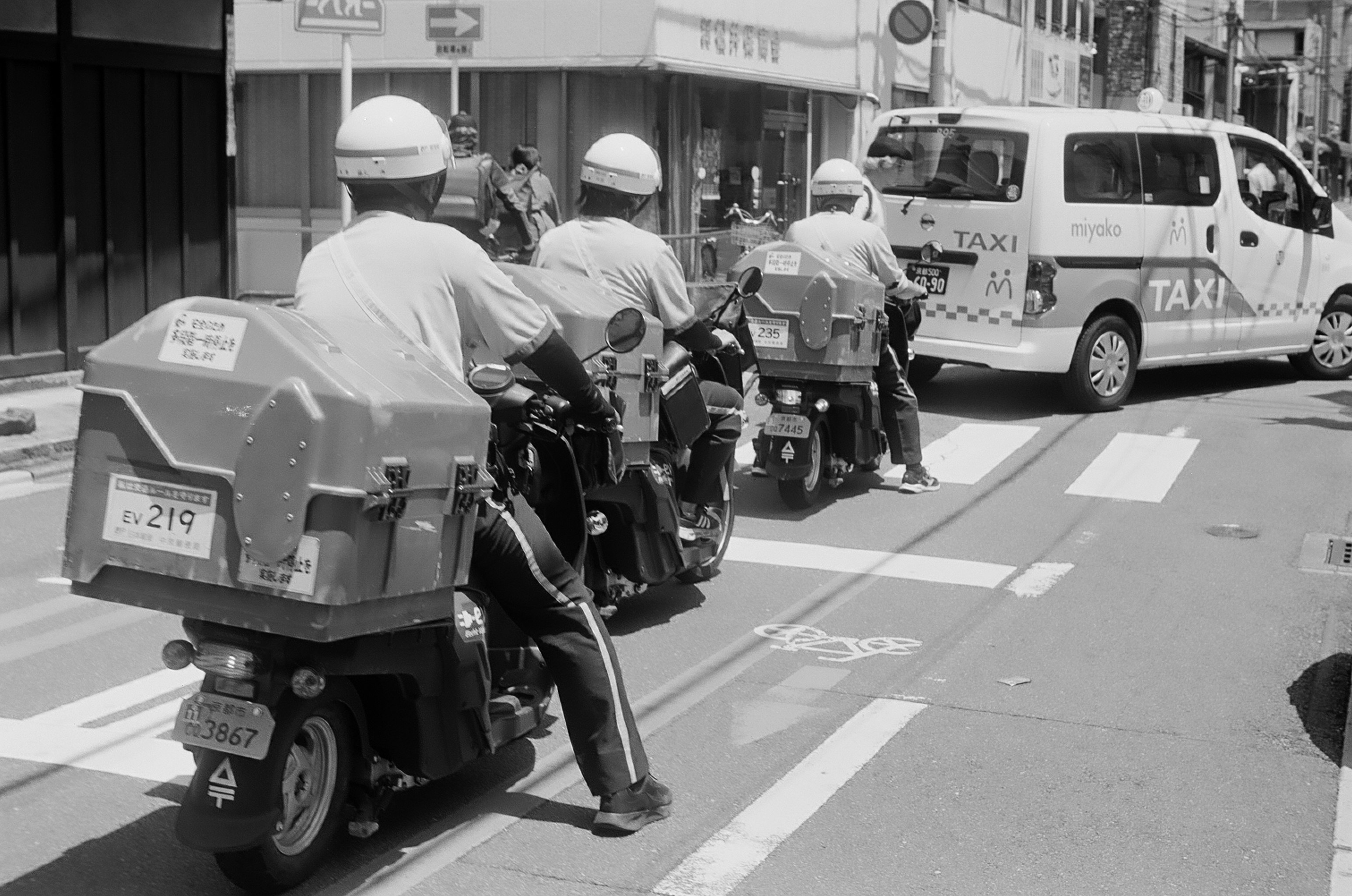 路地の交差点で並ぶバイクとタクシー