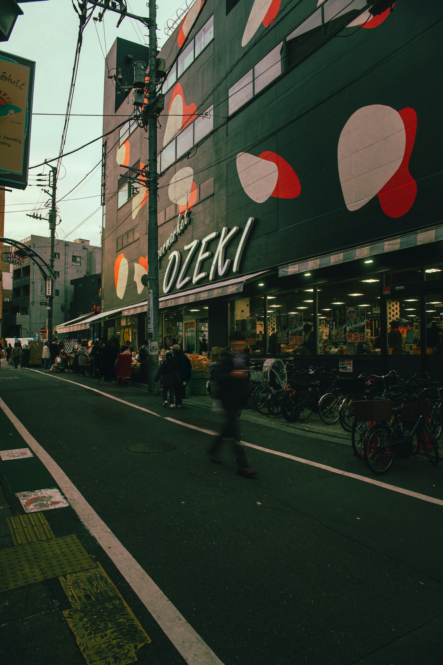 Vista de la calle con la tienda Ozeki y diseños abstractos coloridos bicicletas estacionadas a lo largo de la carretera