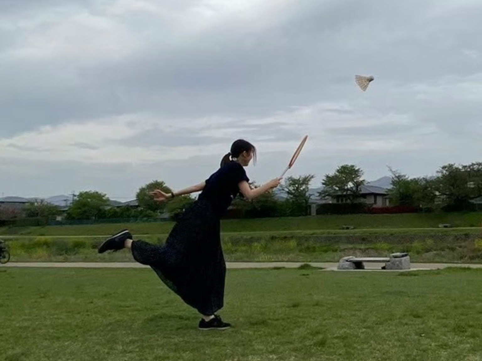 Persona in abbigliamento nero che lancia un aeroplano di carta in un parco