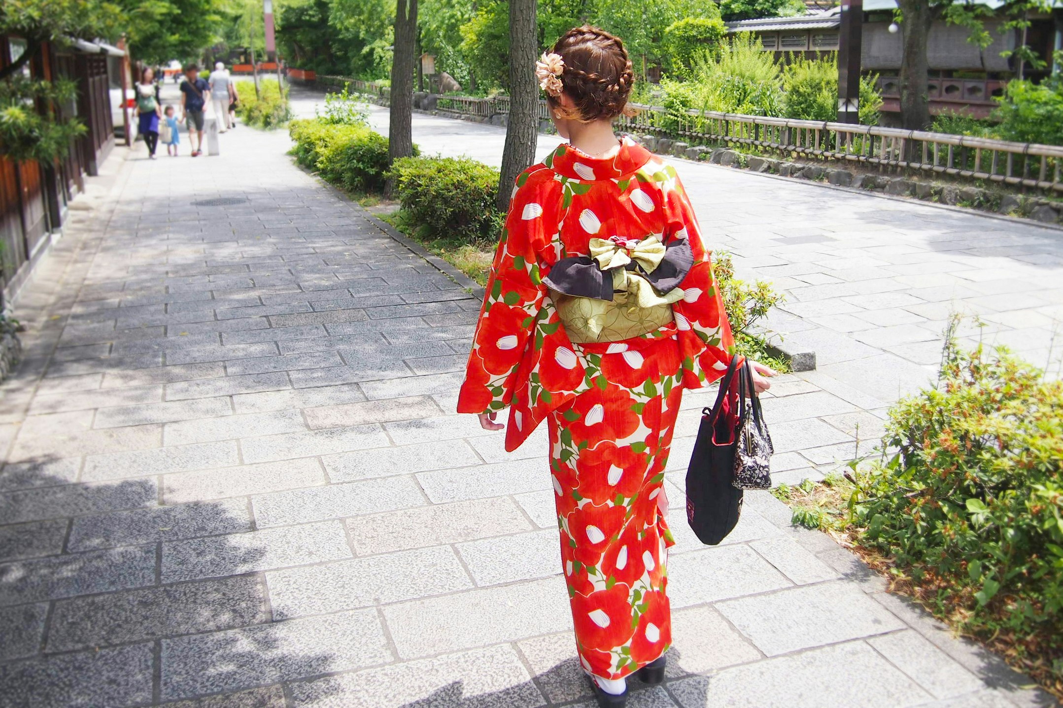 woman in a red patterned kimono walking along a garden path