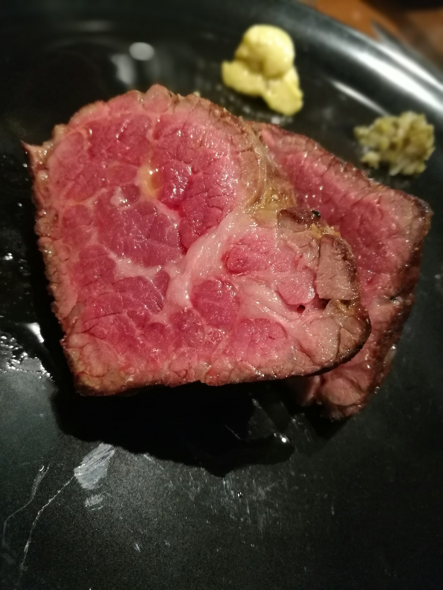 黑色盘子上的薄切肉和芥末