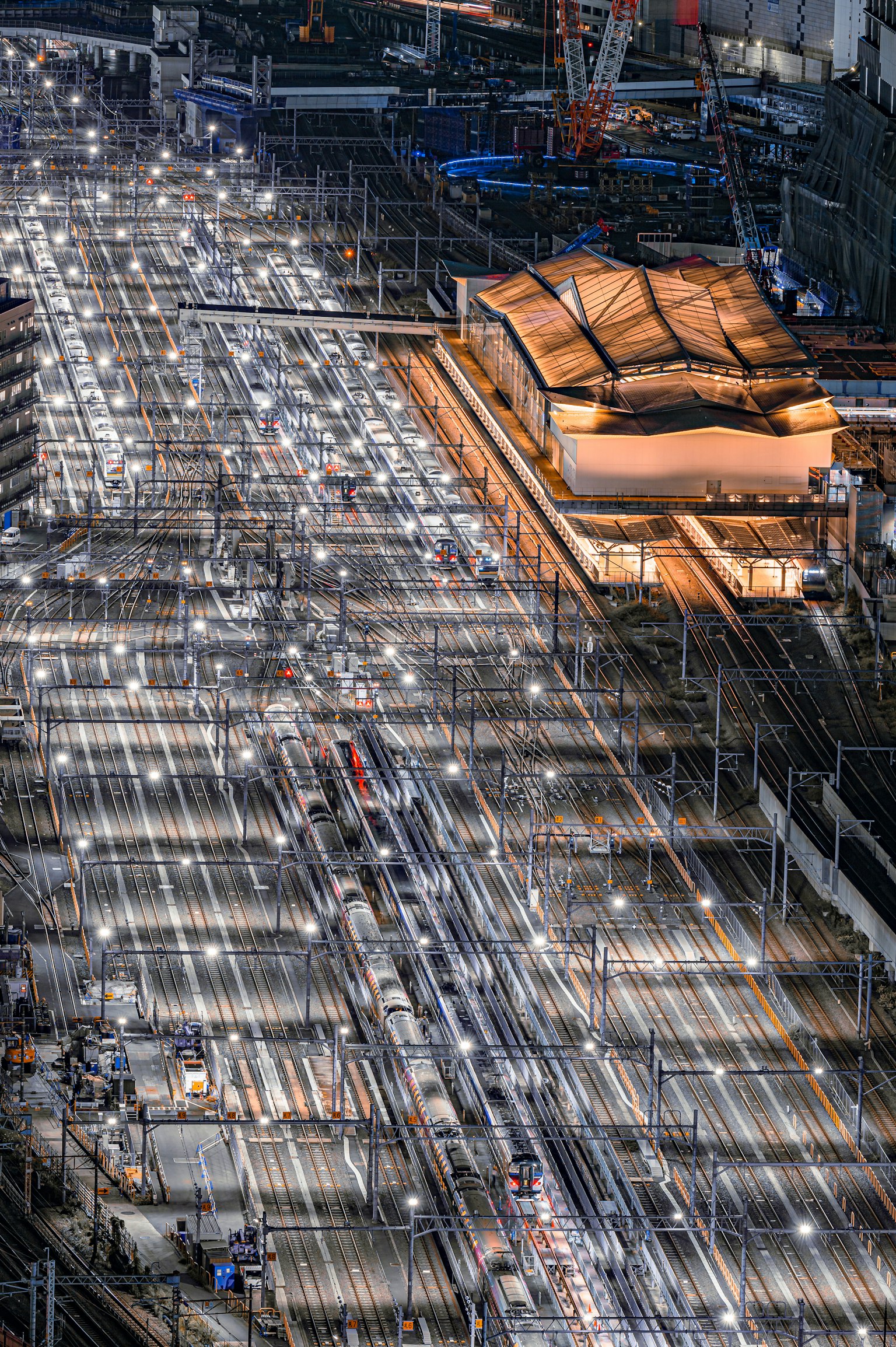 Vista aerea di una stazione ferroviaria illuminata di notte con molteplici binari