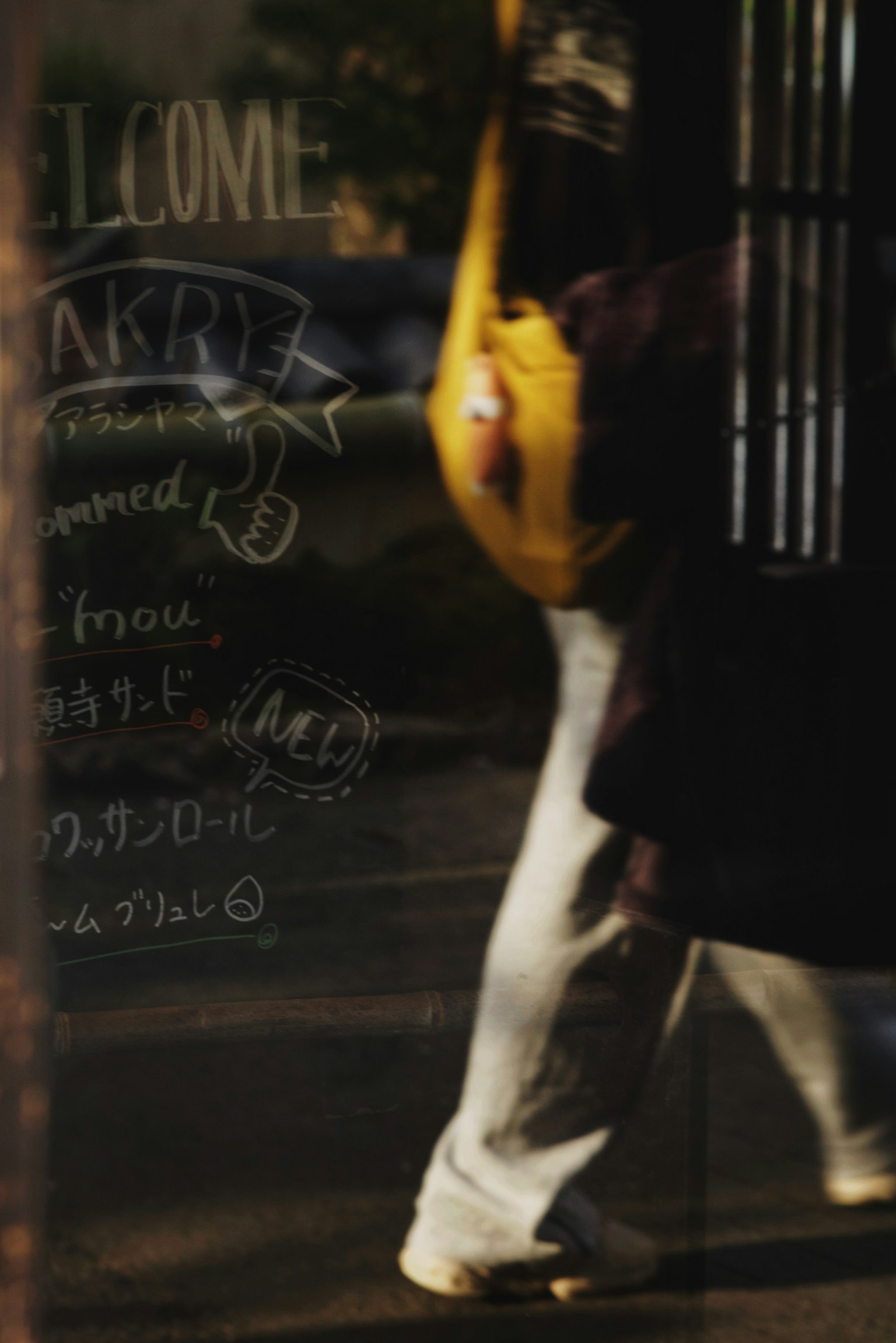 Reflection of a pedestrian with a yellow bag in a window