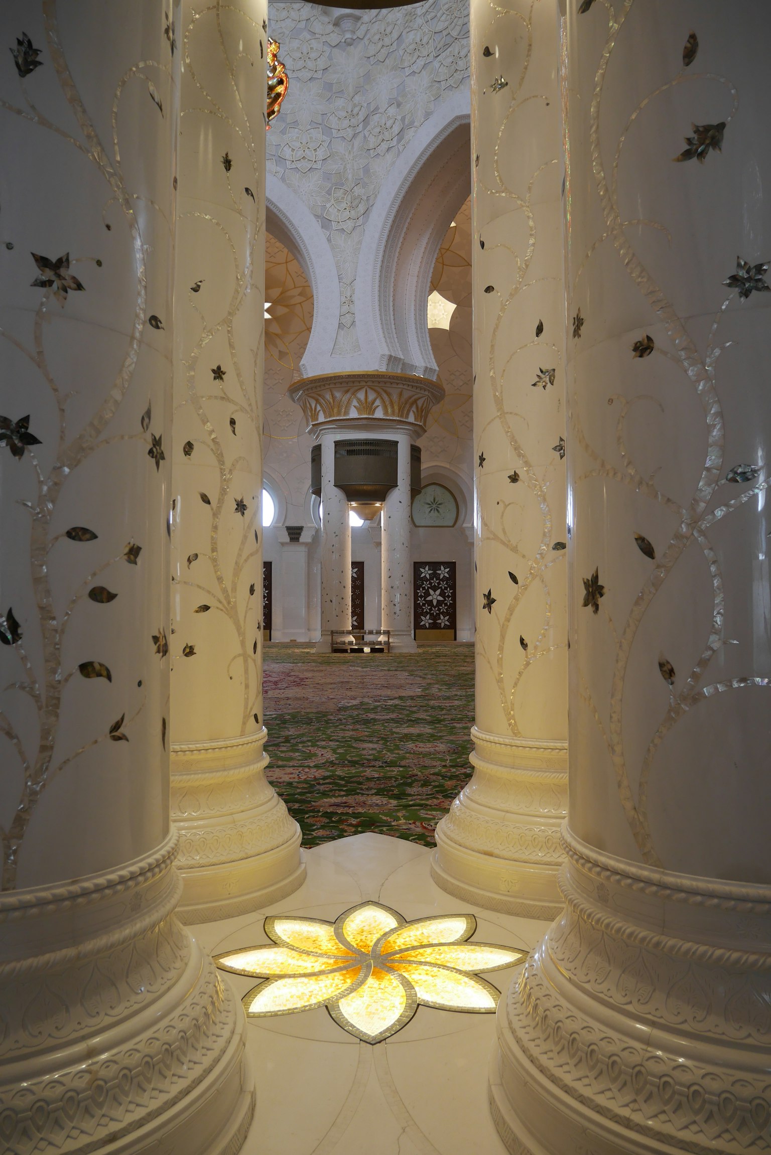 Vista interna con colonne bianche decorate in oro e un design floreale luminoso sul pavimento