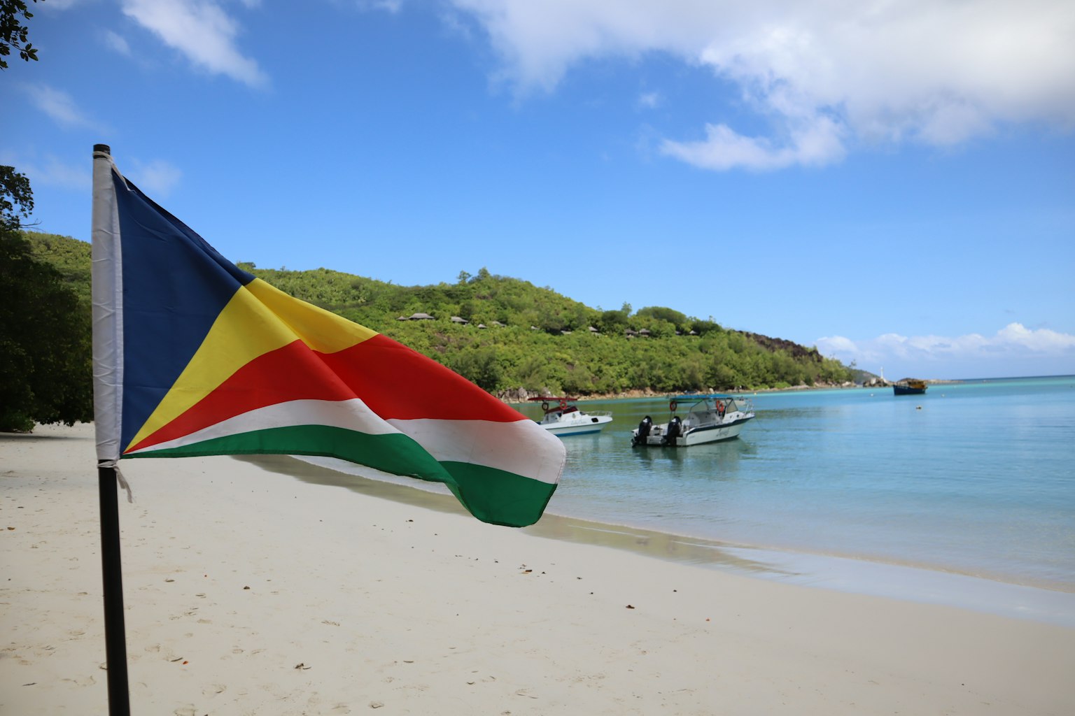 Cờ Seychelles phấp phới trên bãi biển với những chiếc thuyền ở phía sau