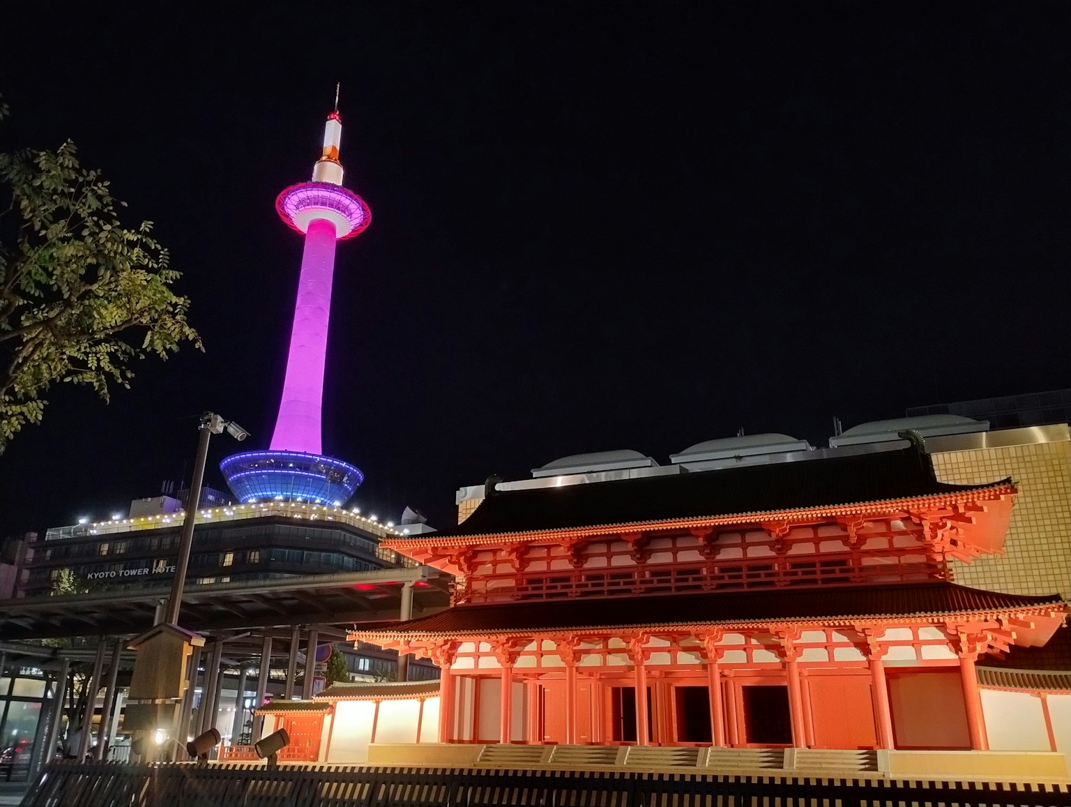 夜晚粉紅色照亮的京都塔與傳統紅色建築的對比
