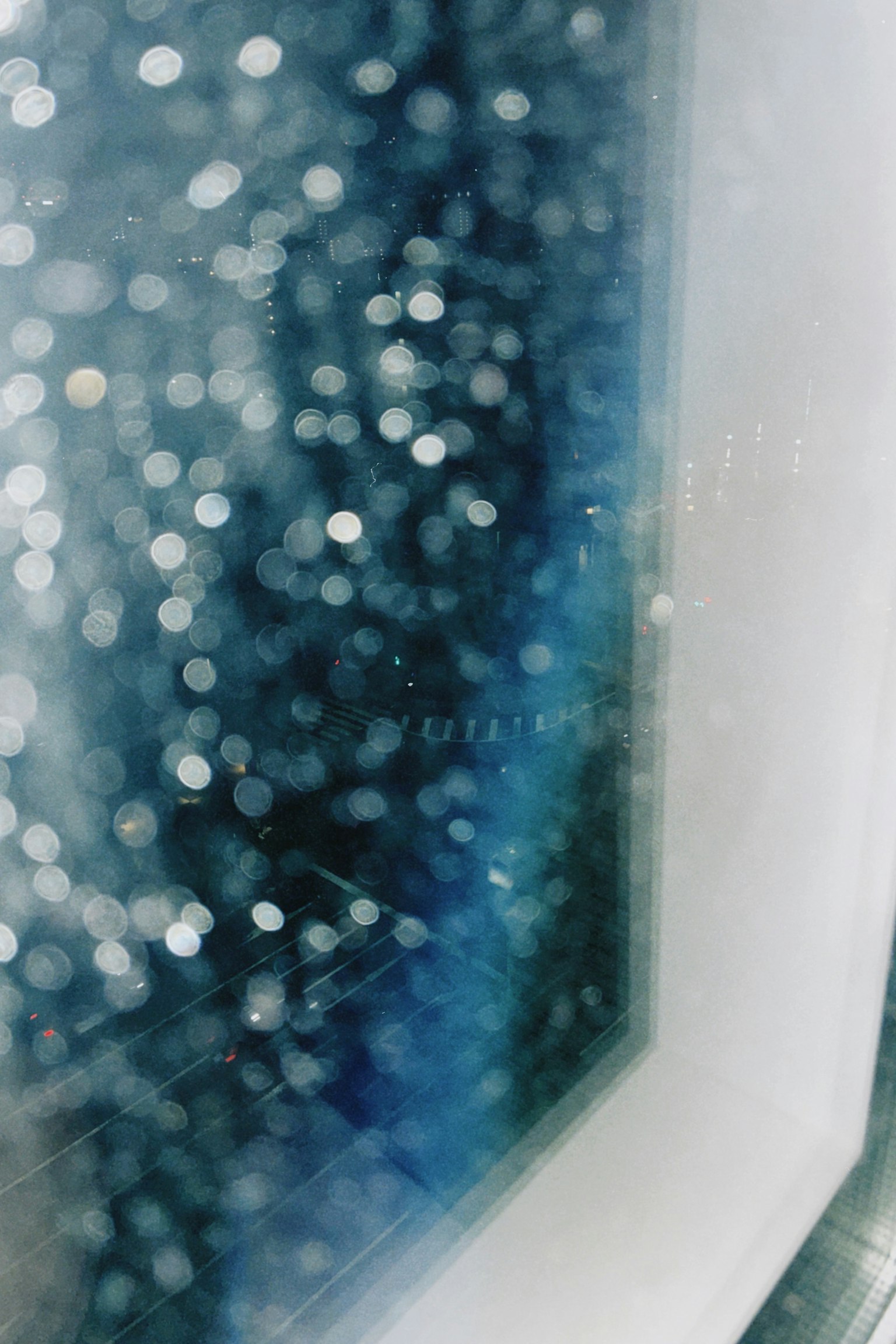 青い背景にぼやけた光の点が映る窓の近くの画像