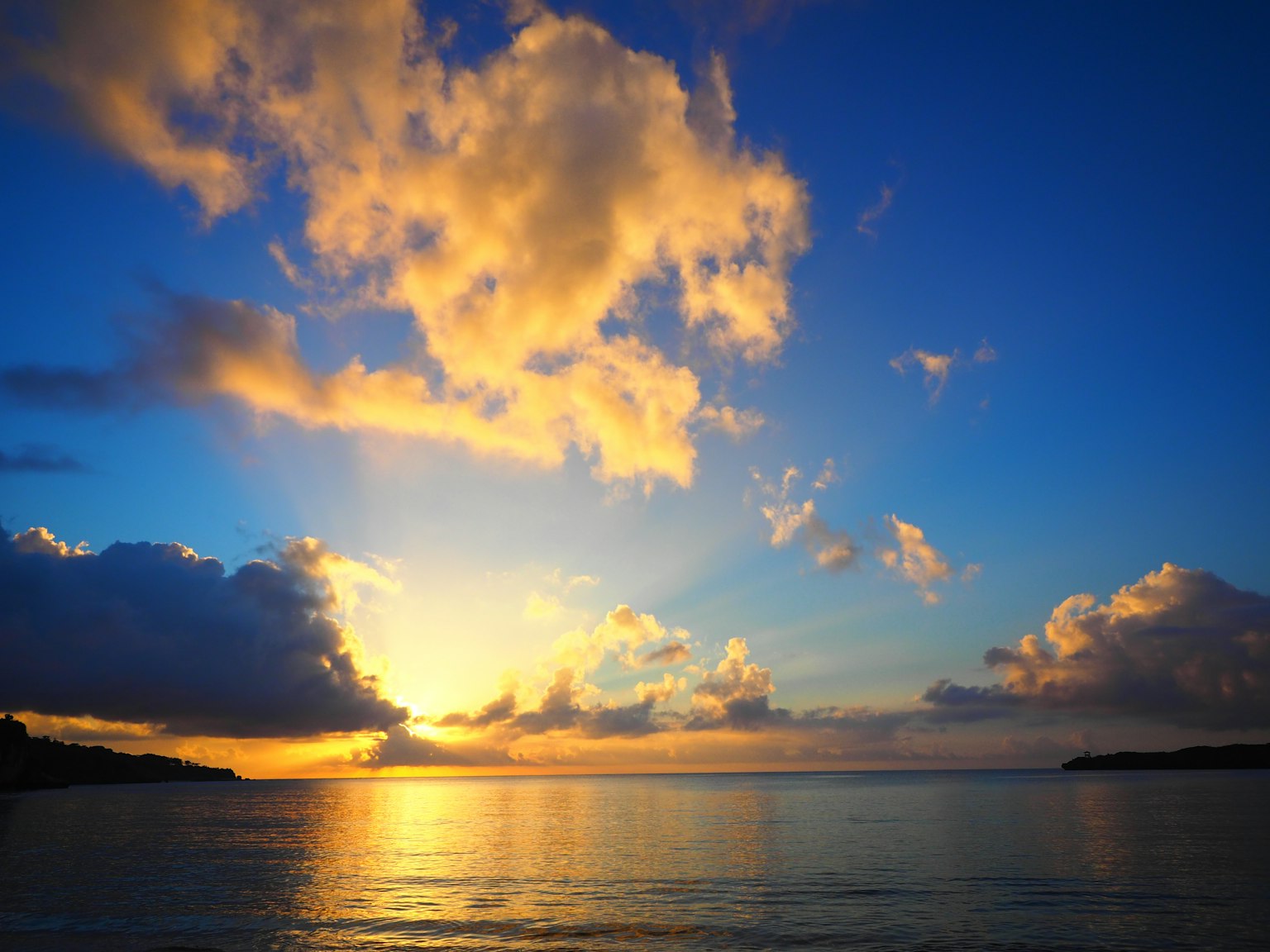 Pemandangan matahari terbenam yang indah di atas laut dengan awan di langit biru