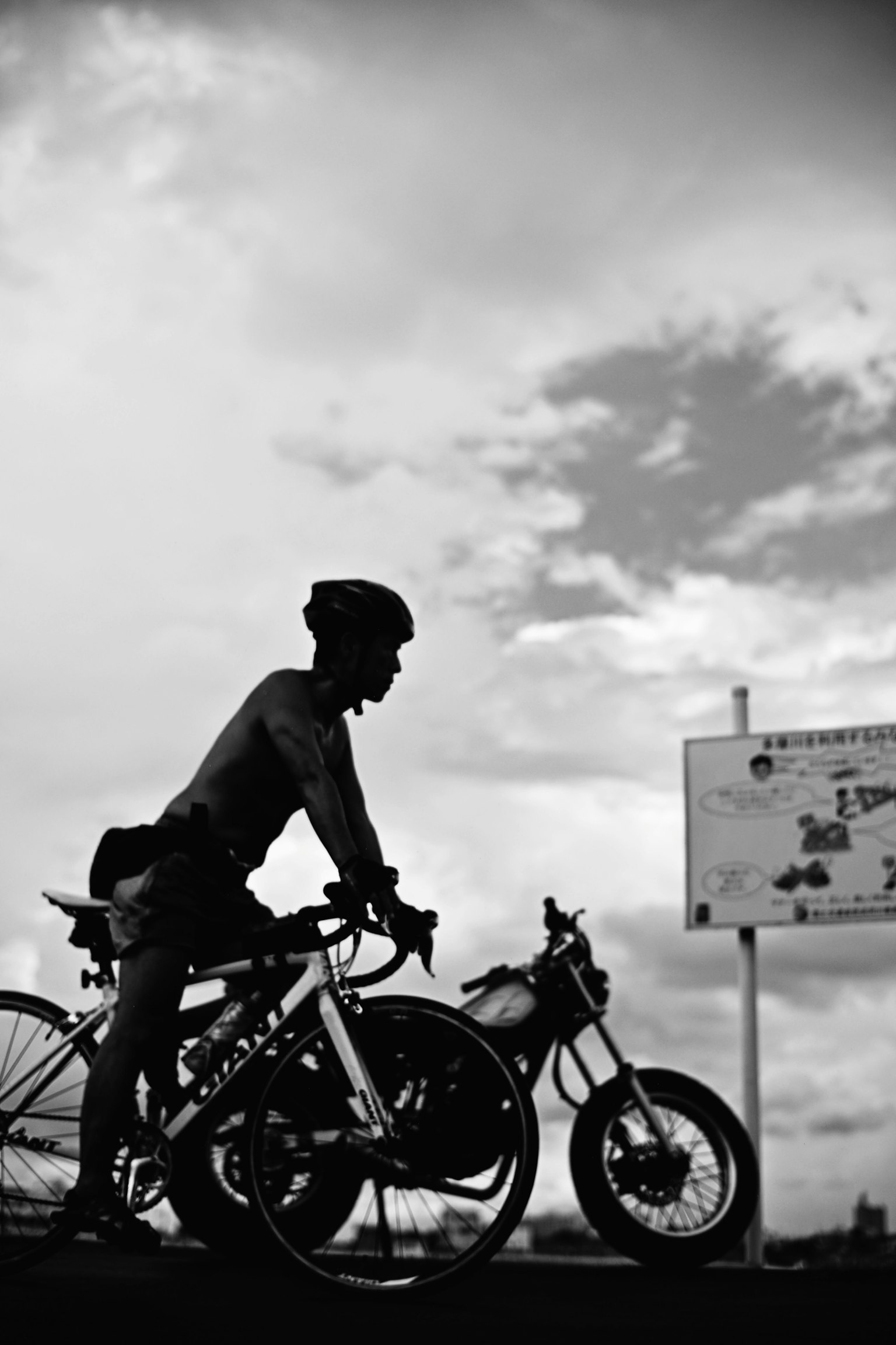 Silhouette d'un homme debout à côté d'un vélo et d'une moto