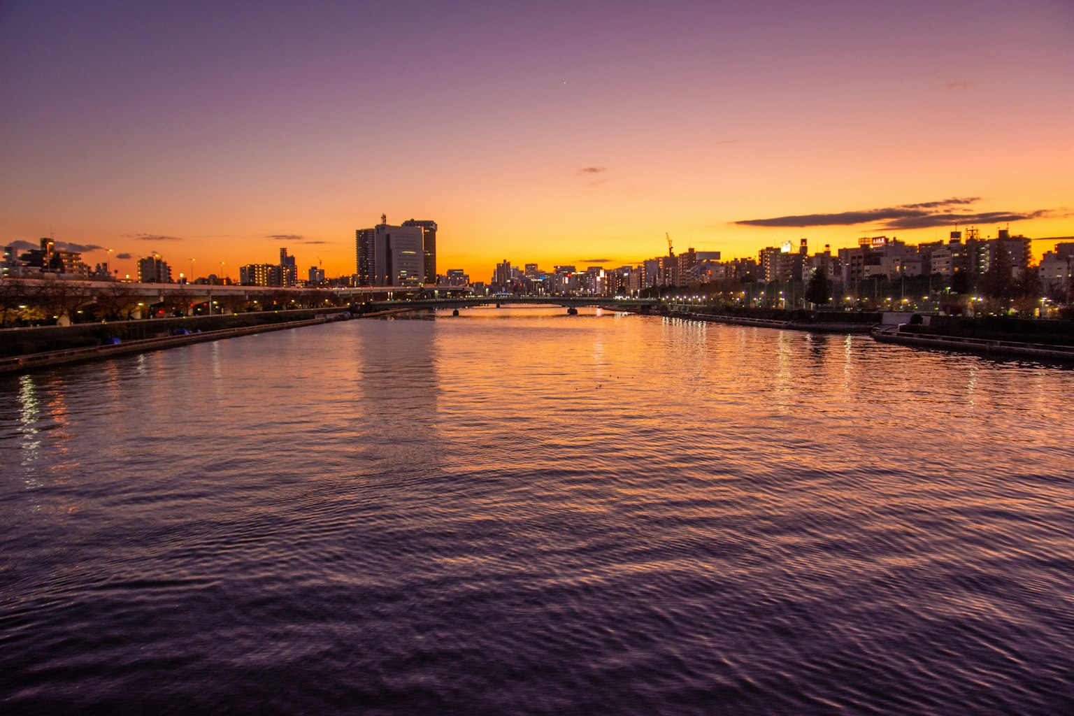 Schöne Flussansicht bei Sonnenuntergang mit Stadtsilhouette
