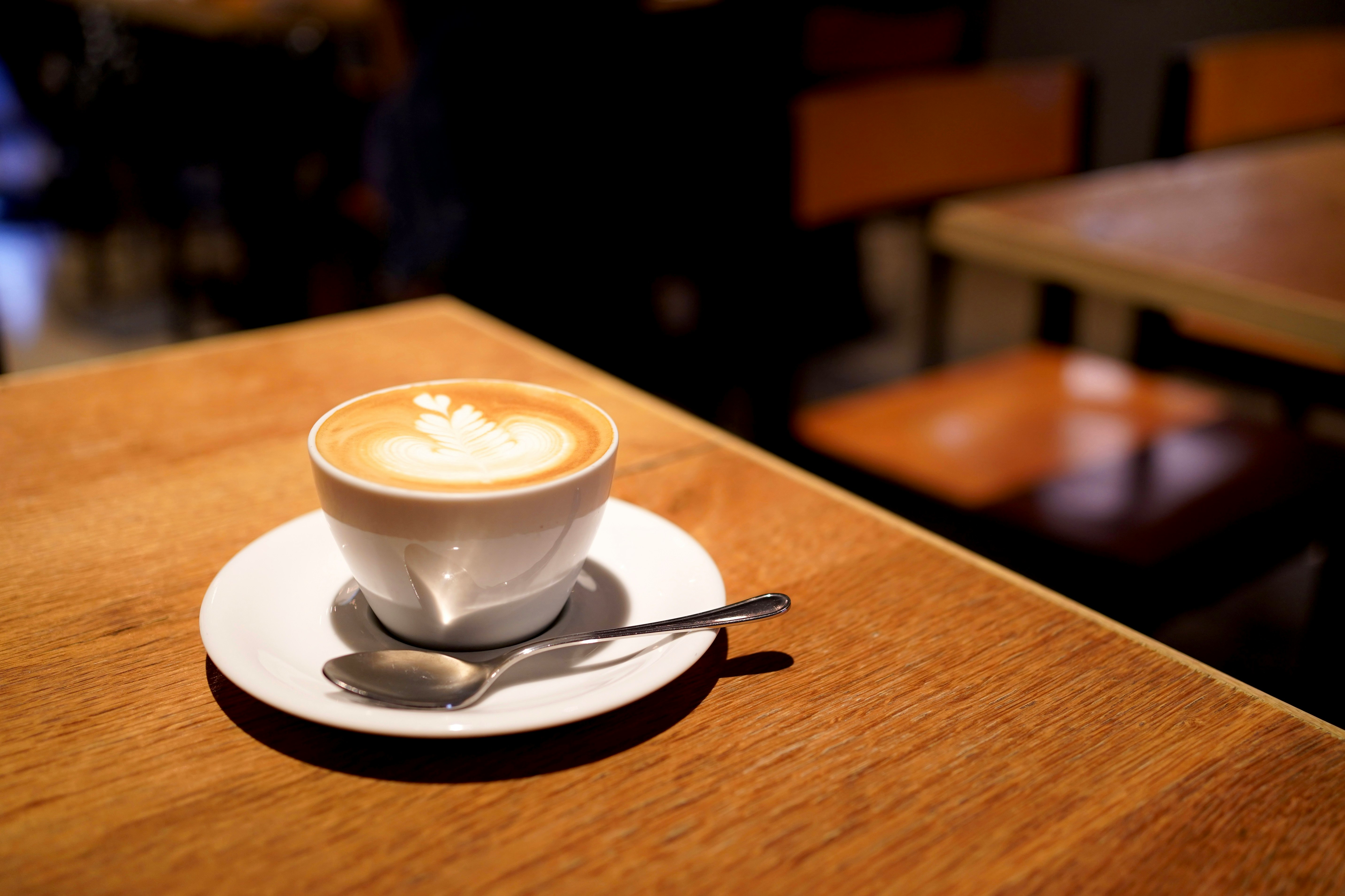 木のテーブルに置かれたラテアートのカフェ画像