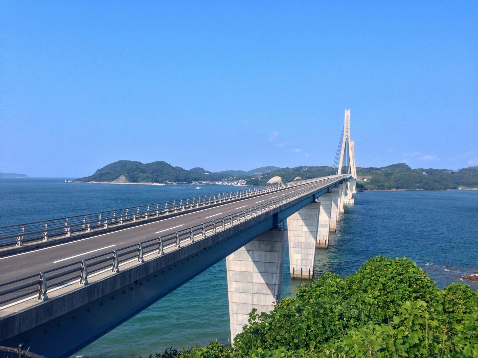 Un hermoso puente que cruza un mar azul con follaje verde