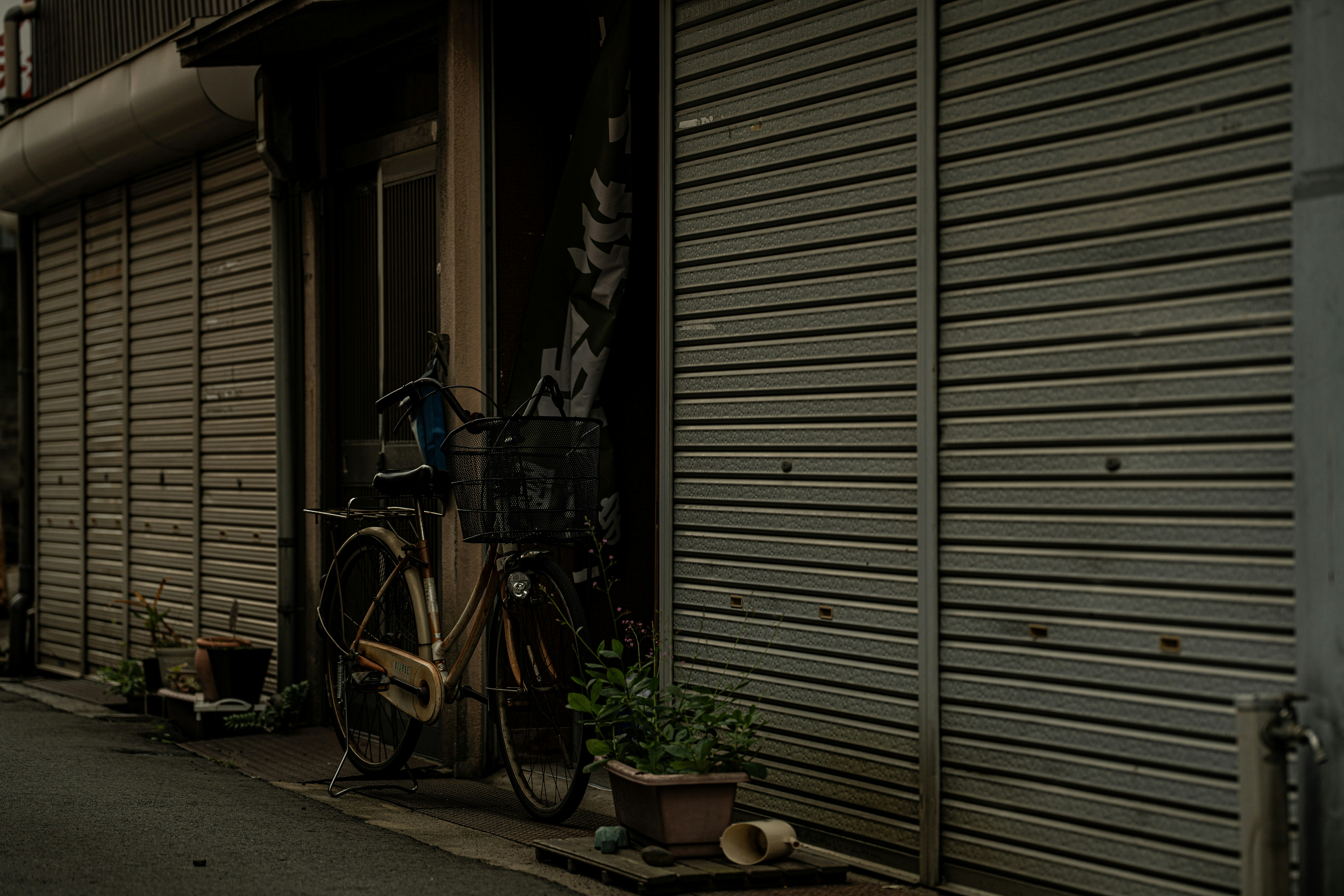 閉ざされたシャッター商店街の路地に並ぶ自転車