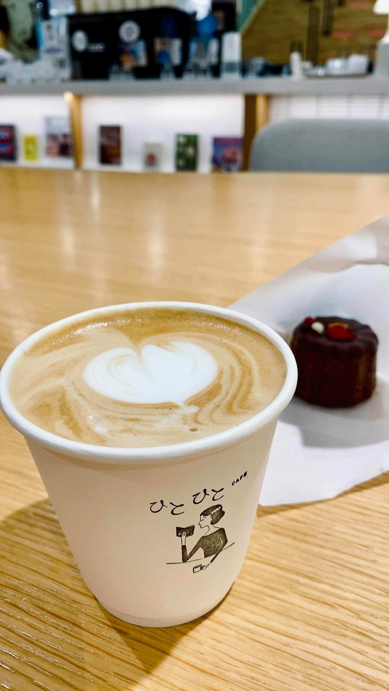 Kaffee Latte mit Herzdesign und einem kleinen Dessert auf einem Holztisch