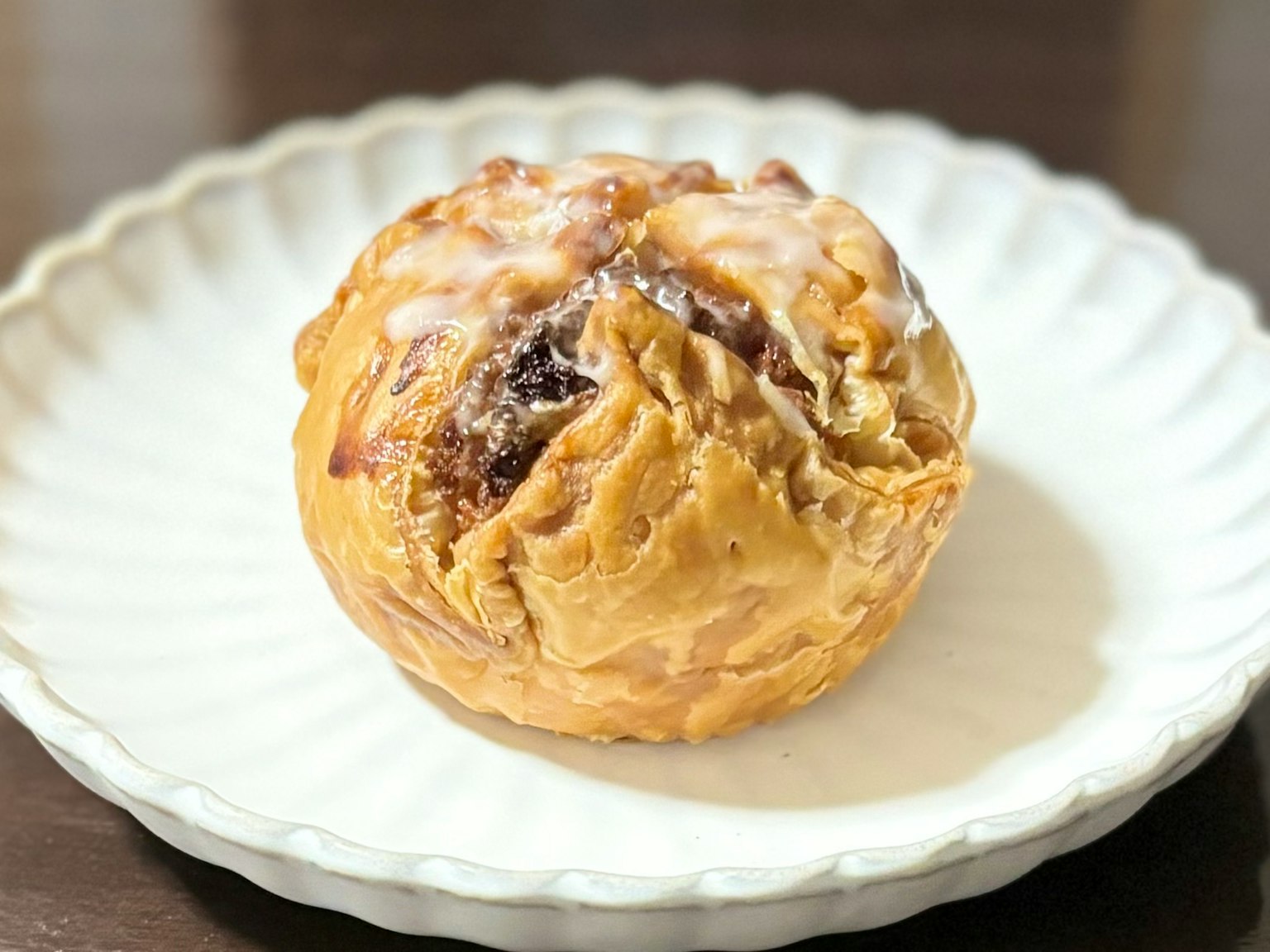Baked pastry with icing on top placed on a white plate