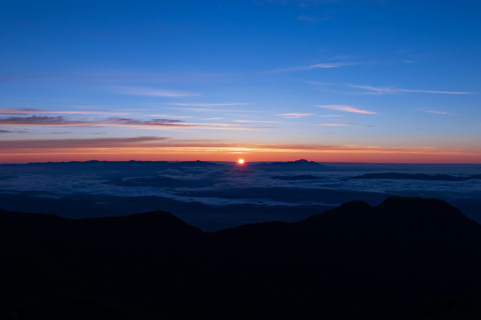 Eindrucksvoller Sonnenaufgang über Bergsilhouetten mit lebhaftem blauen Himmel