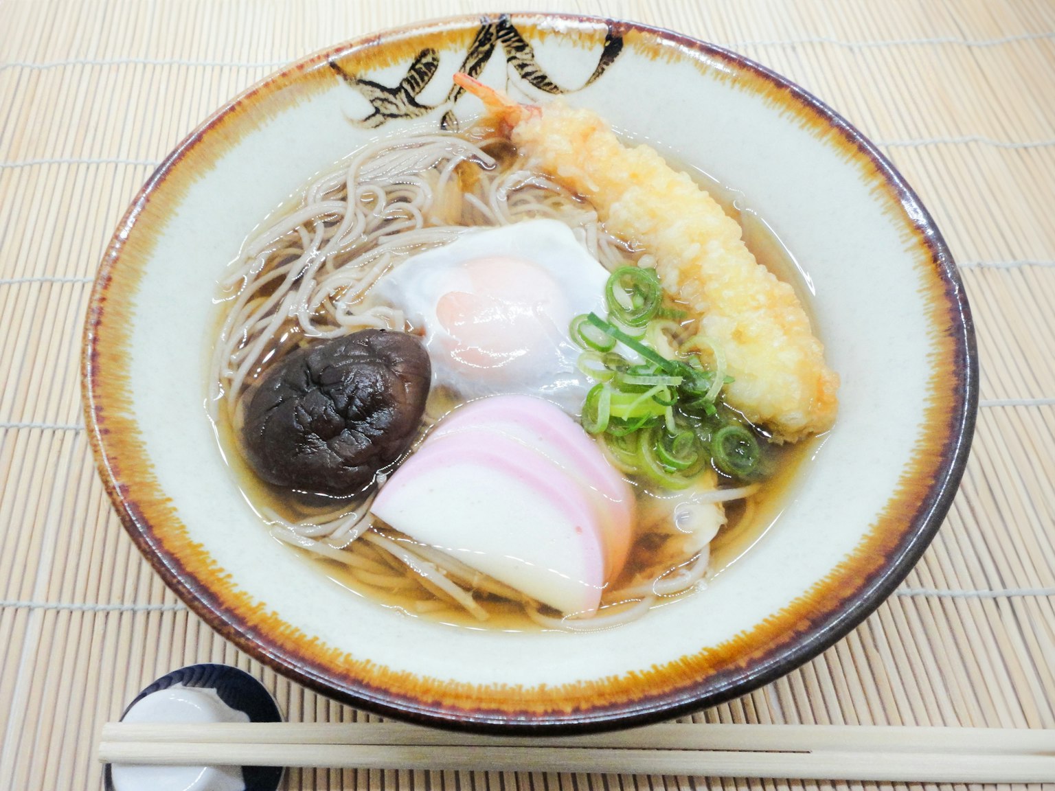 Un bol de nouilles soba garni de crevettes tempura et de légumes dans un style japonais traditionnel