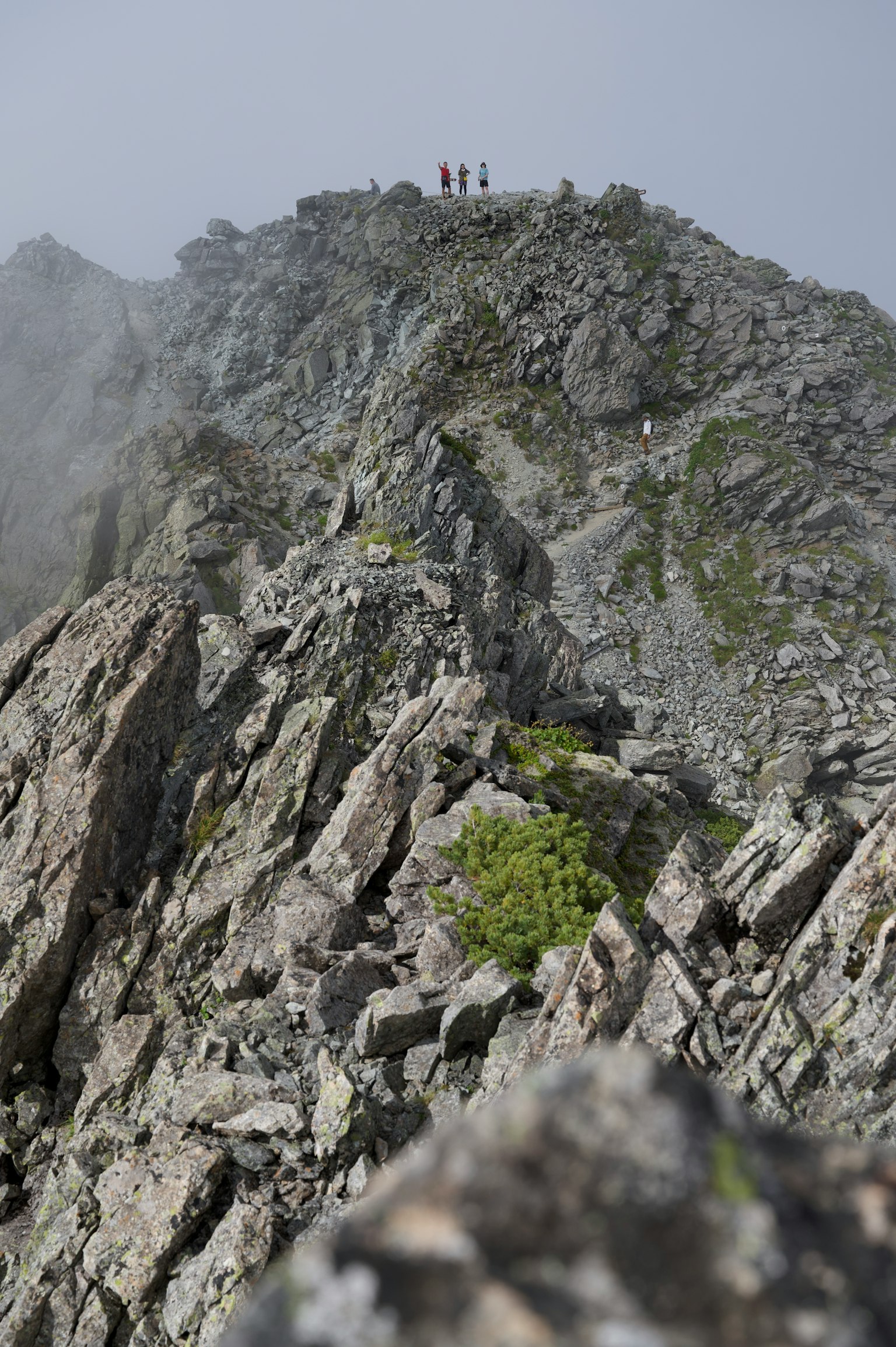 Randonneurs se tenant au sommet d'une montagne rocheuse enveloppée de brume