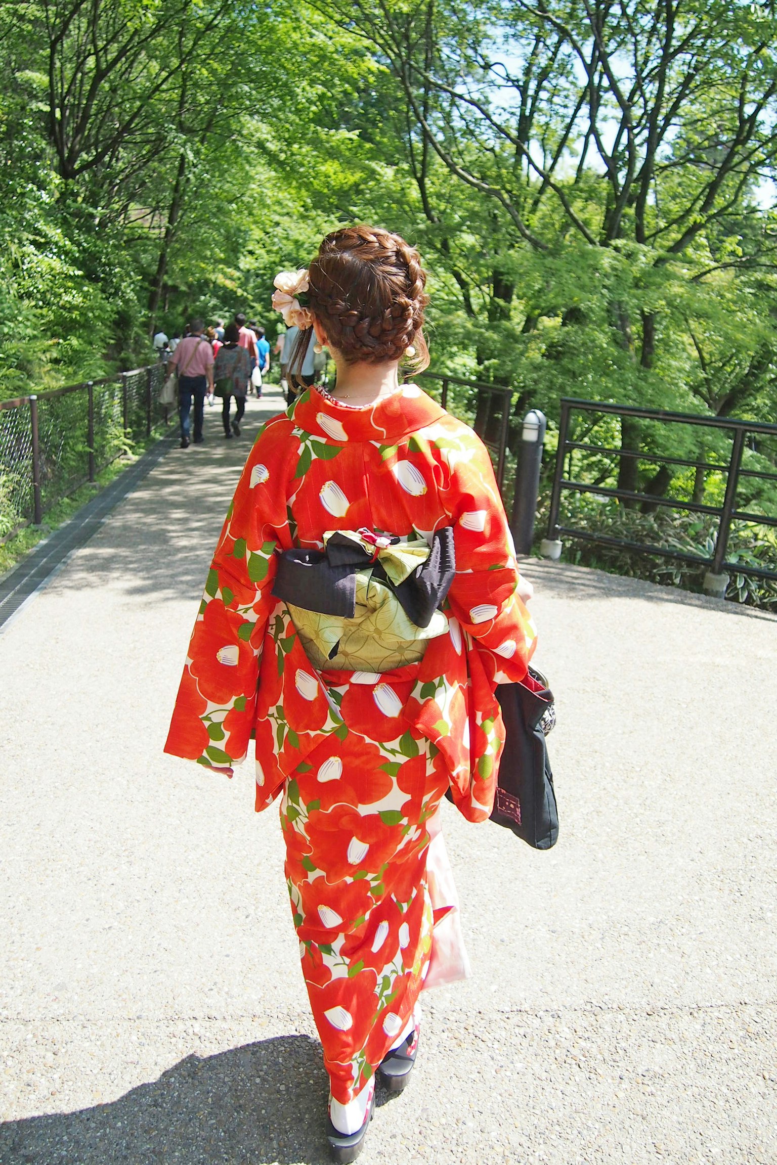 Frau im roten Kimono mit Erdbeermuster geht in einer malerischen Umgebung